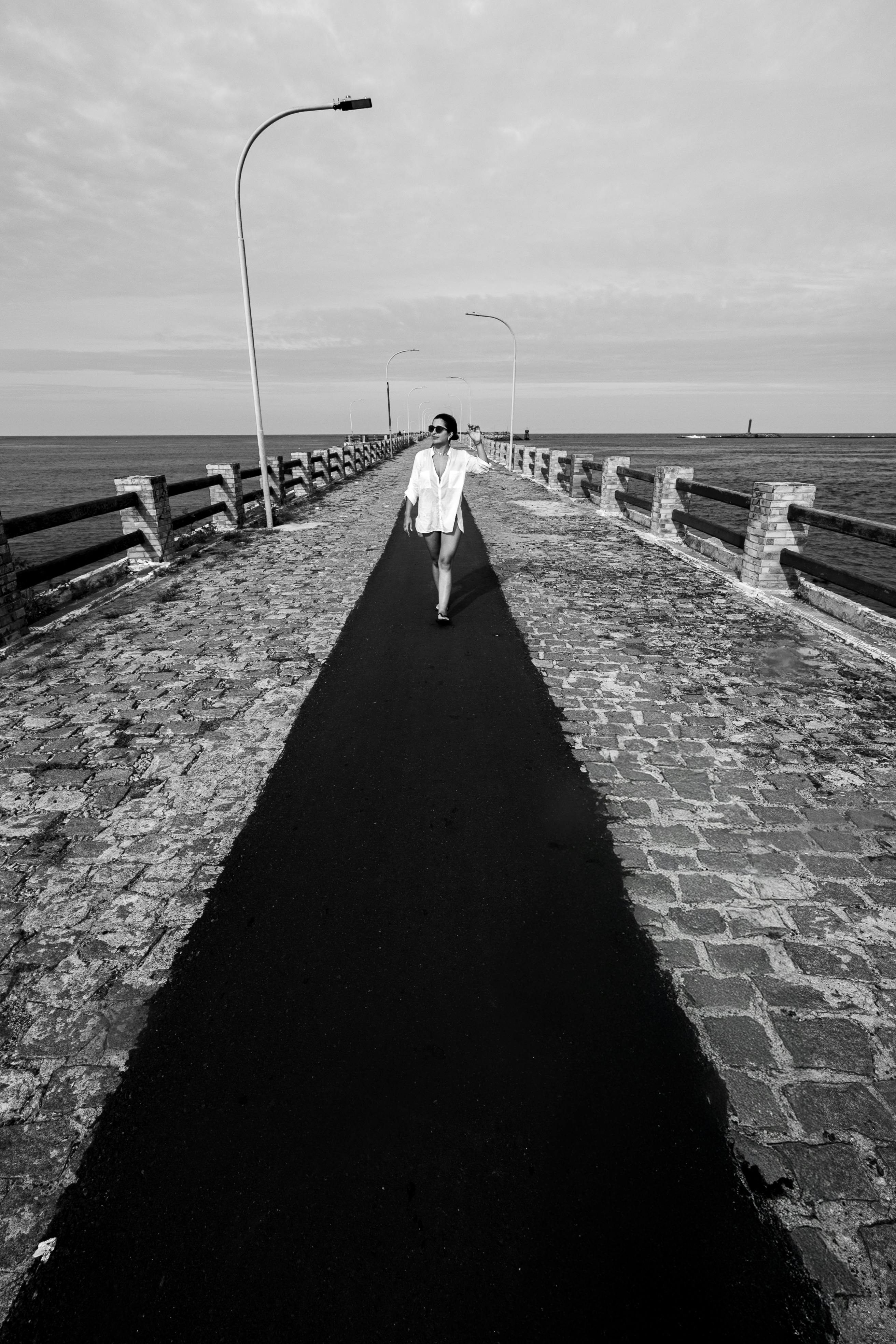 De franc Una foto en blanc i negre d'una persona caminant per un moll a Natal, Brasil. Perspectiva dramàtica. Foto d'estoc