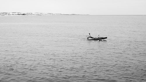 Free Fishermen in a boat on a serene sea near Natal, Brazil. Tranquil black and white scene. Stock Photo