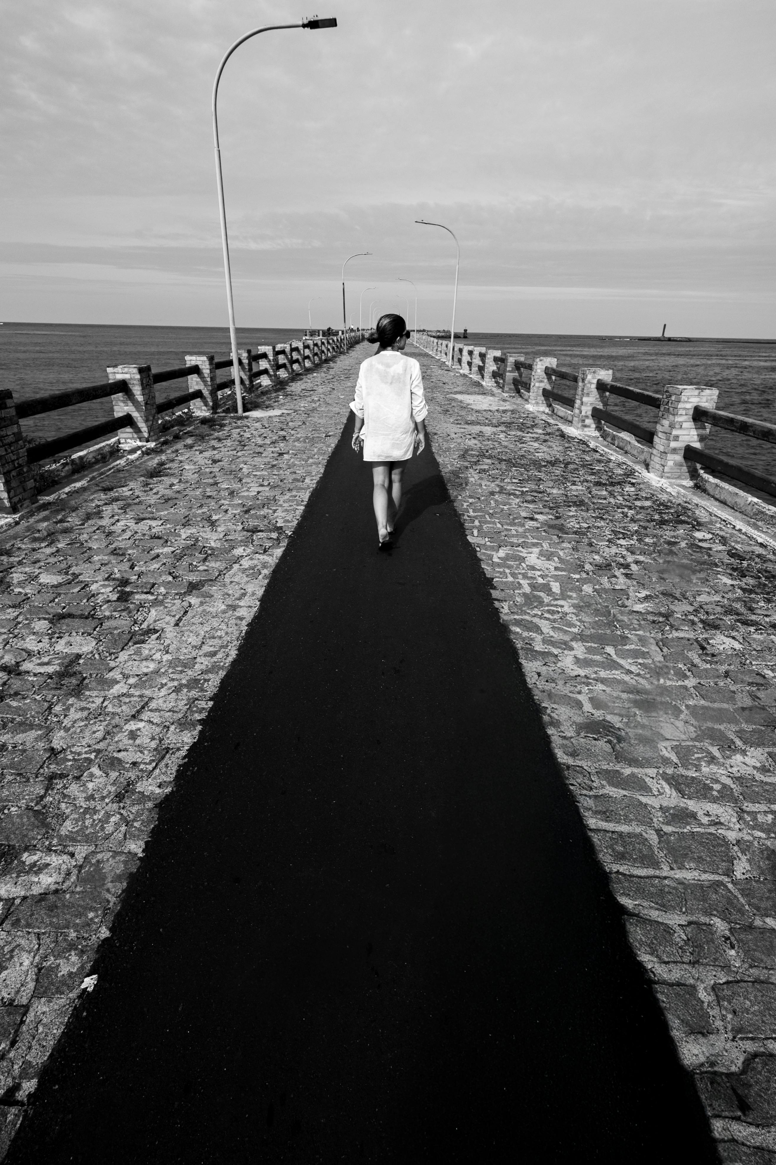 Gratuit Une silhouette solitaire marchant sur un pont pavé à Natal, au Brésil, dans une composition en noir et blanc. Photos