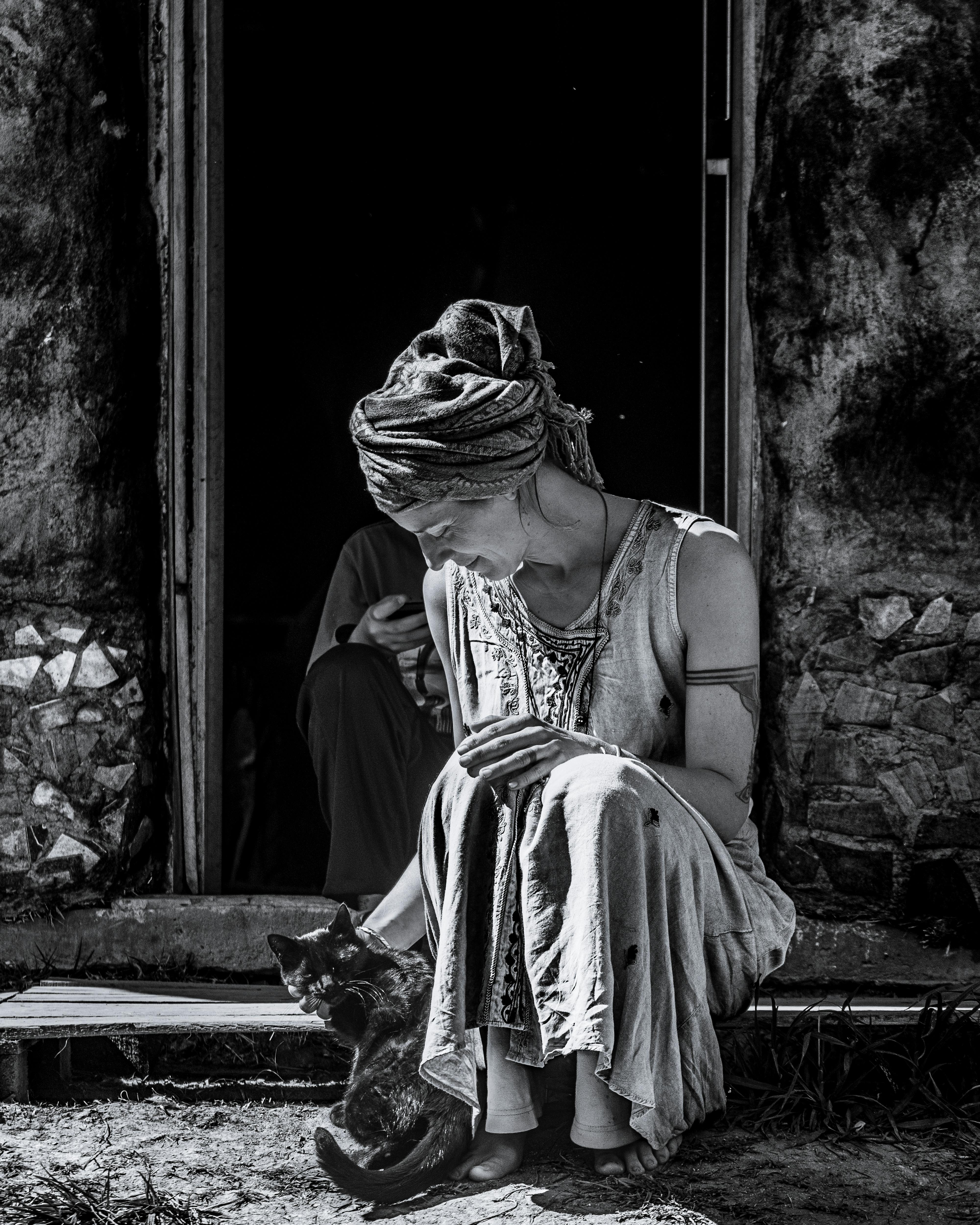 Gratuit O femeie în ținută rustică așezată cu o pisică la o ușă, Buenos Aires. Fotografie de stoc