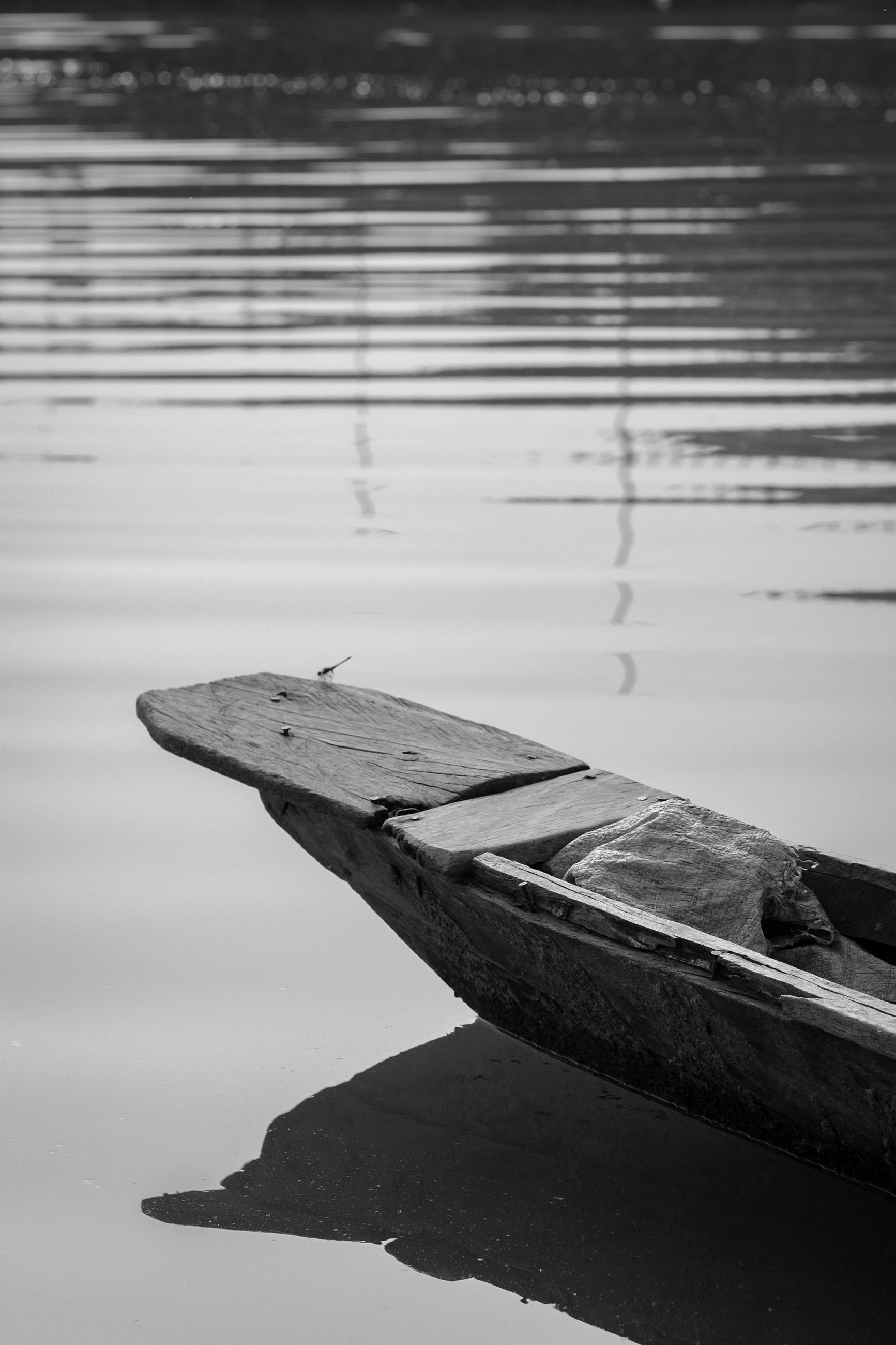 Gratuit Imagine senină alb-negru a unei bărci de lemn pe o apă liniștită, surprinzând o stare de spirit pașnică și reflexivă. Fotografie de stoc