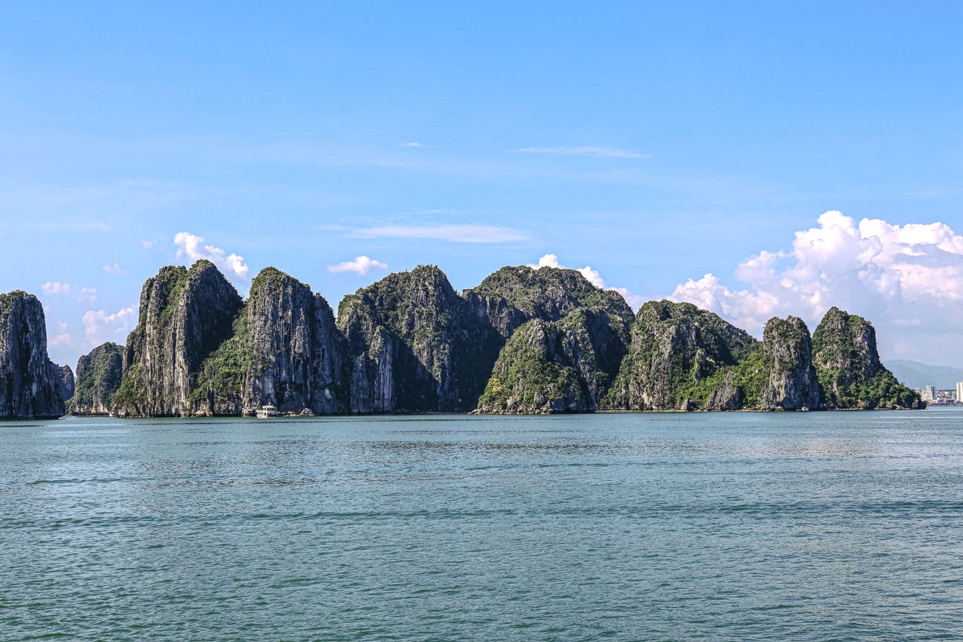 Limestone karsts rising from the water in Ha Long Bay, Vietnam, under a clear sky