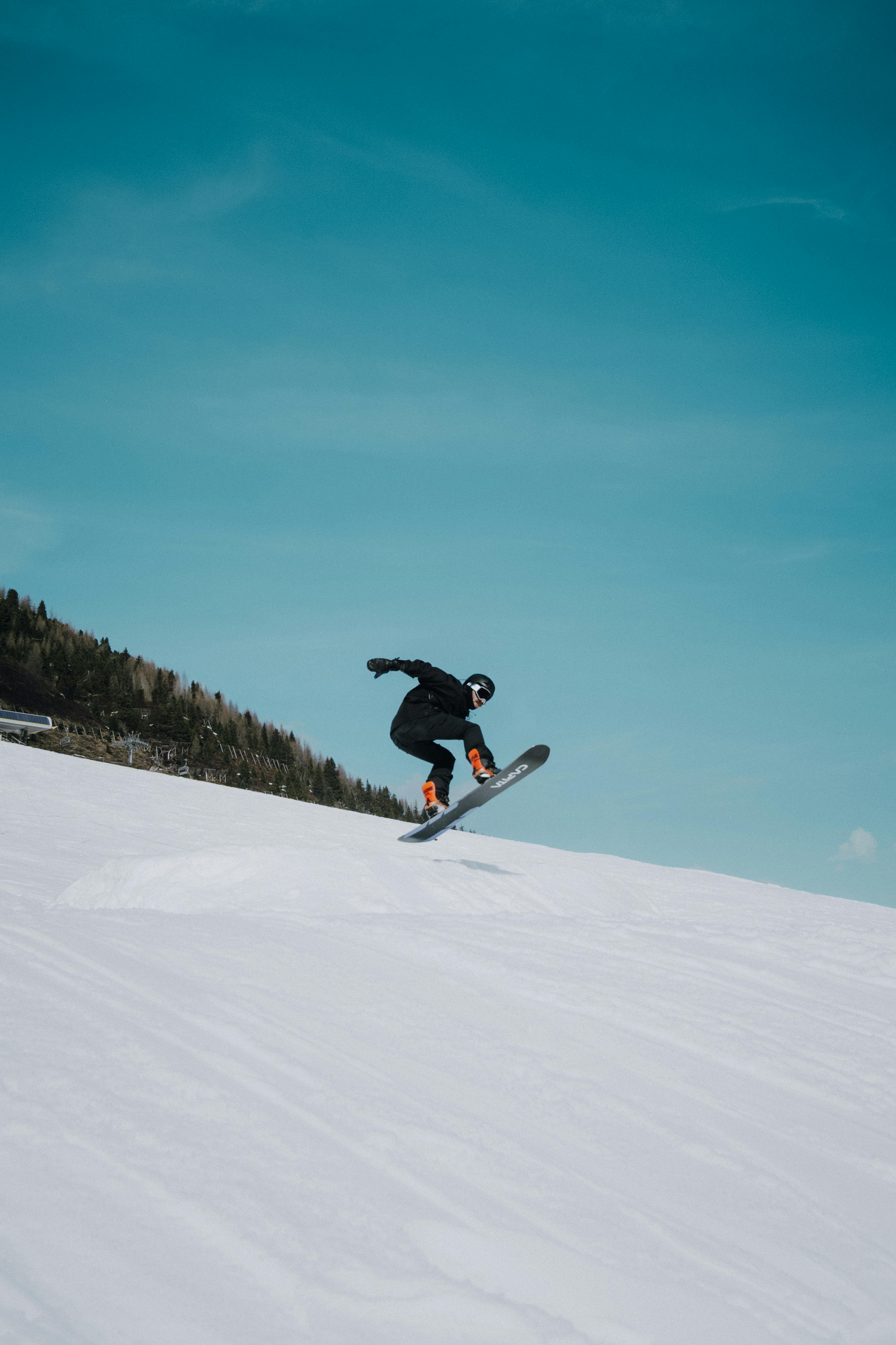 Ücretsiz Avusturya'nın Tirol bölgesindeki Rohrberg'de bir snowboardcu karlı yamaçlarda atlayış yapıyor. Stok Fotoğraflar