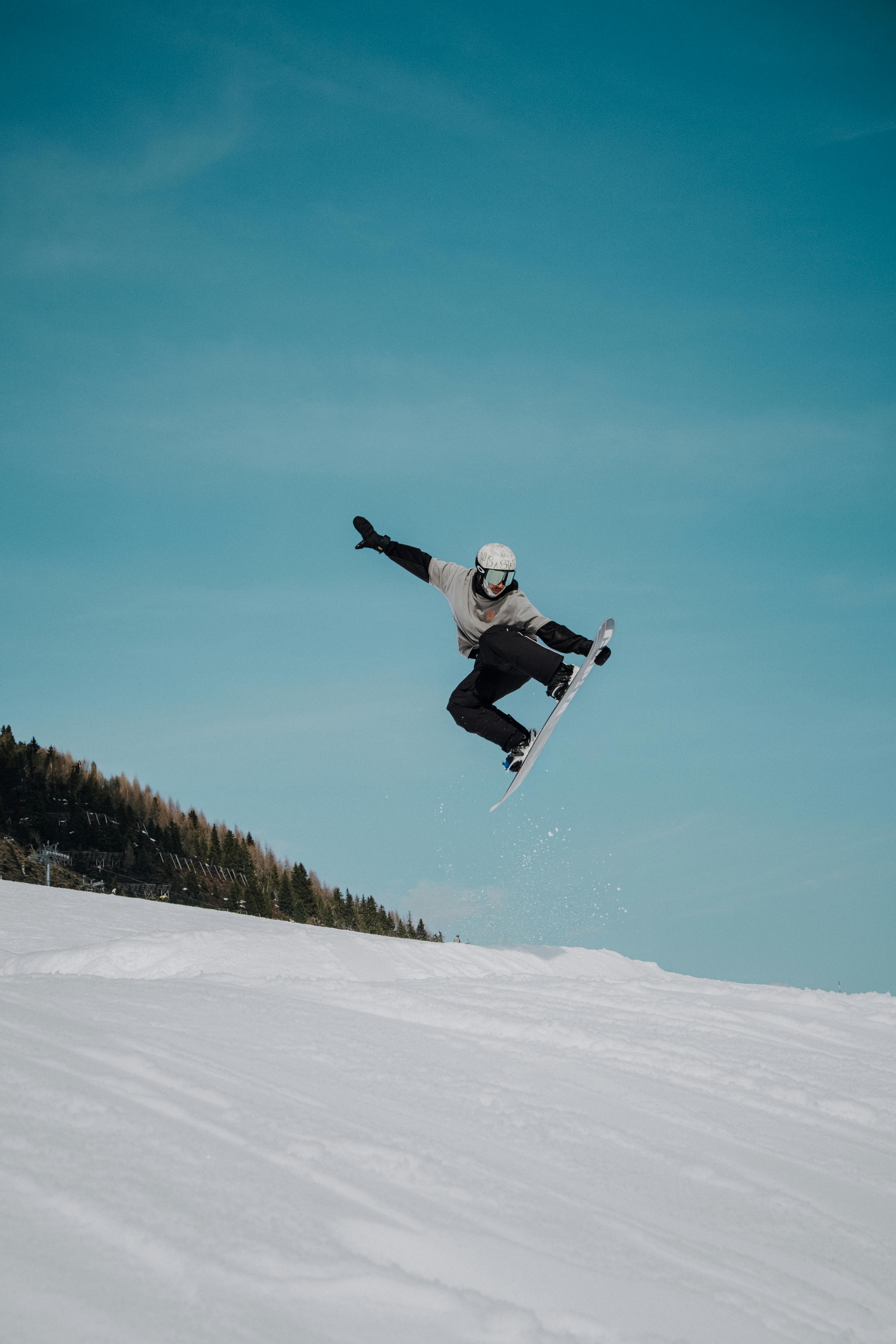 Gratis En snowboarder trækker vejret midt i et hop mod en klarblå himmel i de Tyrolske Alper, Østrig. Lagerfoto