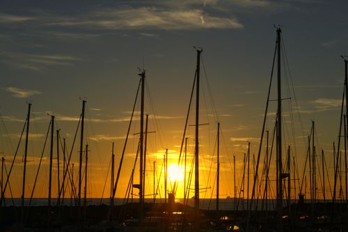 Free Majestic sunset casting a golden glow over anchored sailboats at Lido di Ostia, Lazio, Italy. Stock Photo