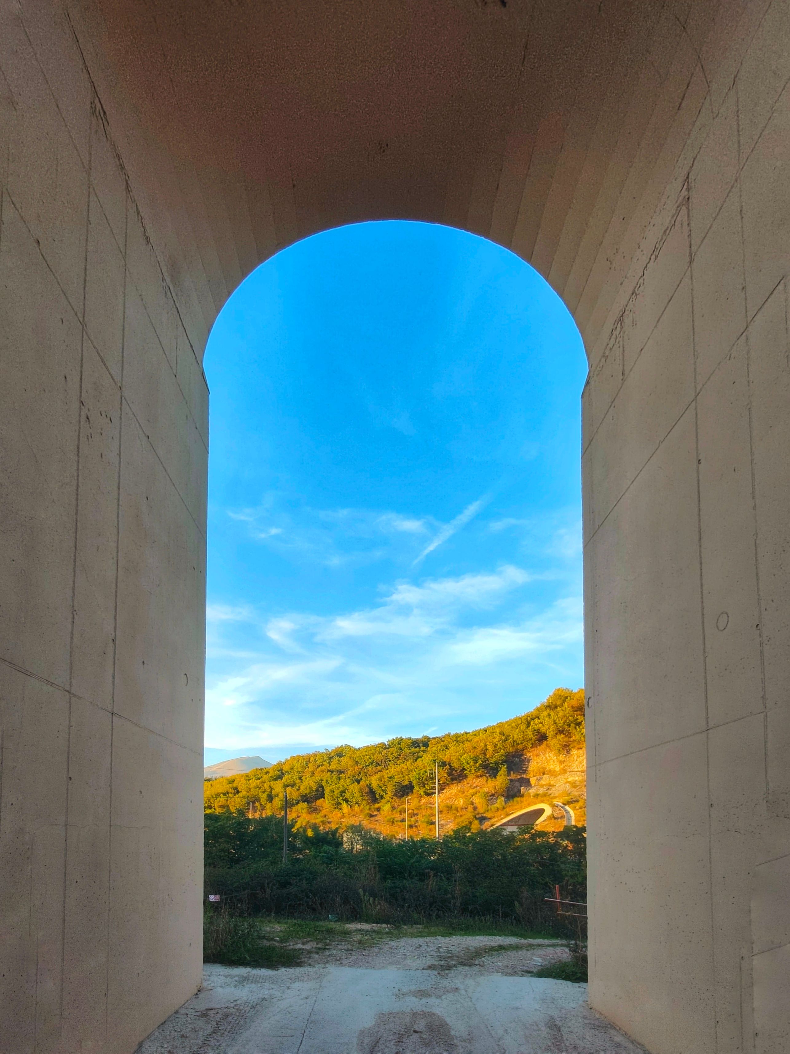 A scenic landscape framed by a large archway in Fossato di Vico, Umbria, Italy.