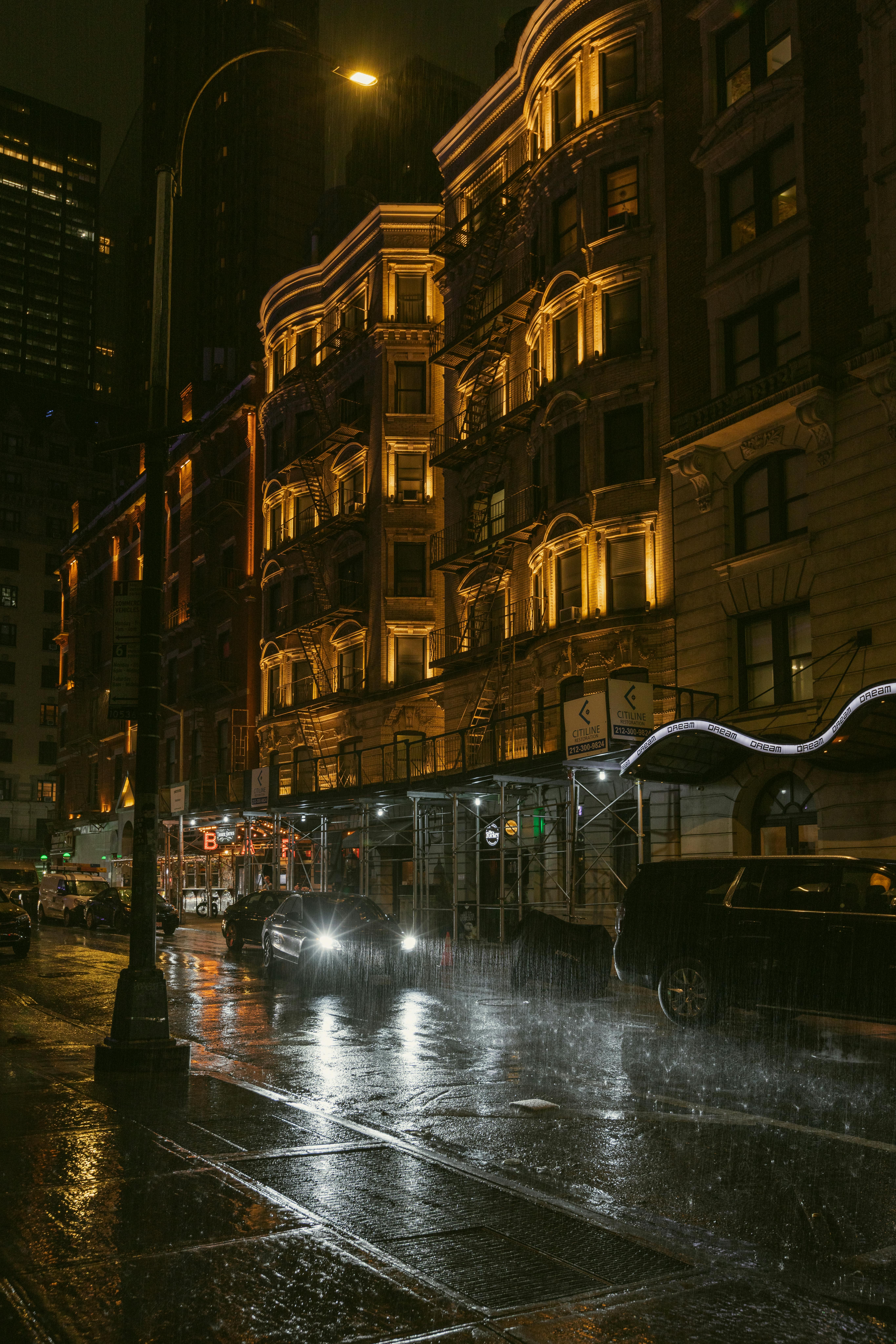免費 雨夜下的紐約街頭，汽車前燈的光芒映照在被雨水浸透的街道上。 圖庫相片