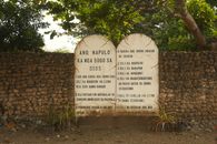 Stone tablet inscribed with religious text, set against a rustic wall in Central Visayas, Philippines.
