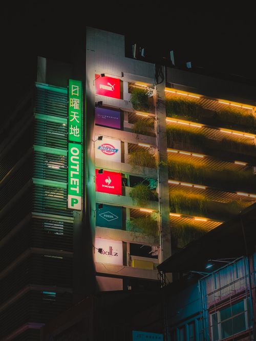 Free Night view of multi-level shopping outlet with illuminated signs and decorative lights. Stock Photo