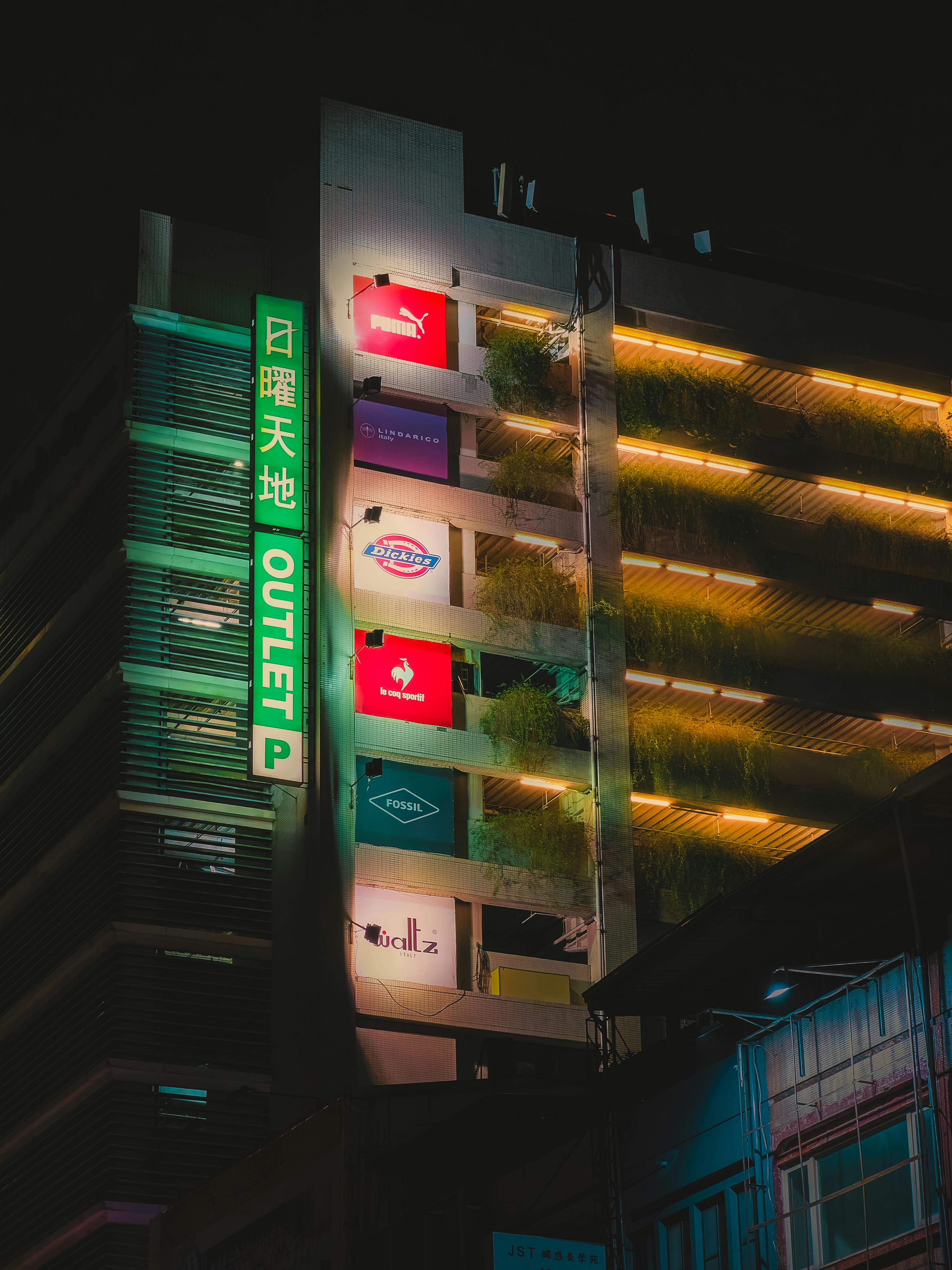 Gratuit Vue nocturne d'un centre commercial à plusieurs niveaux avec enseignes lumineuses et éclairages décoratifs. Photos