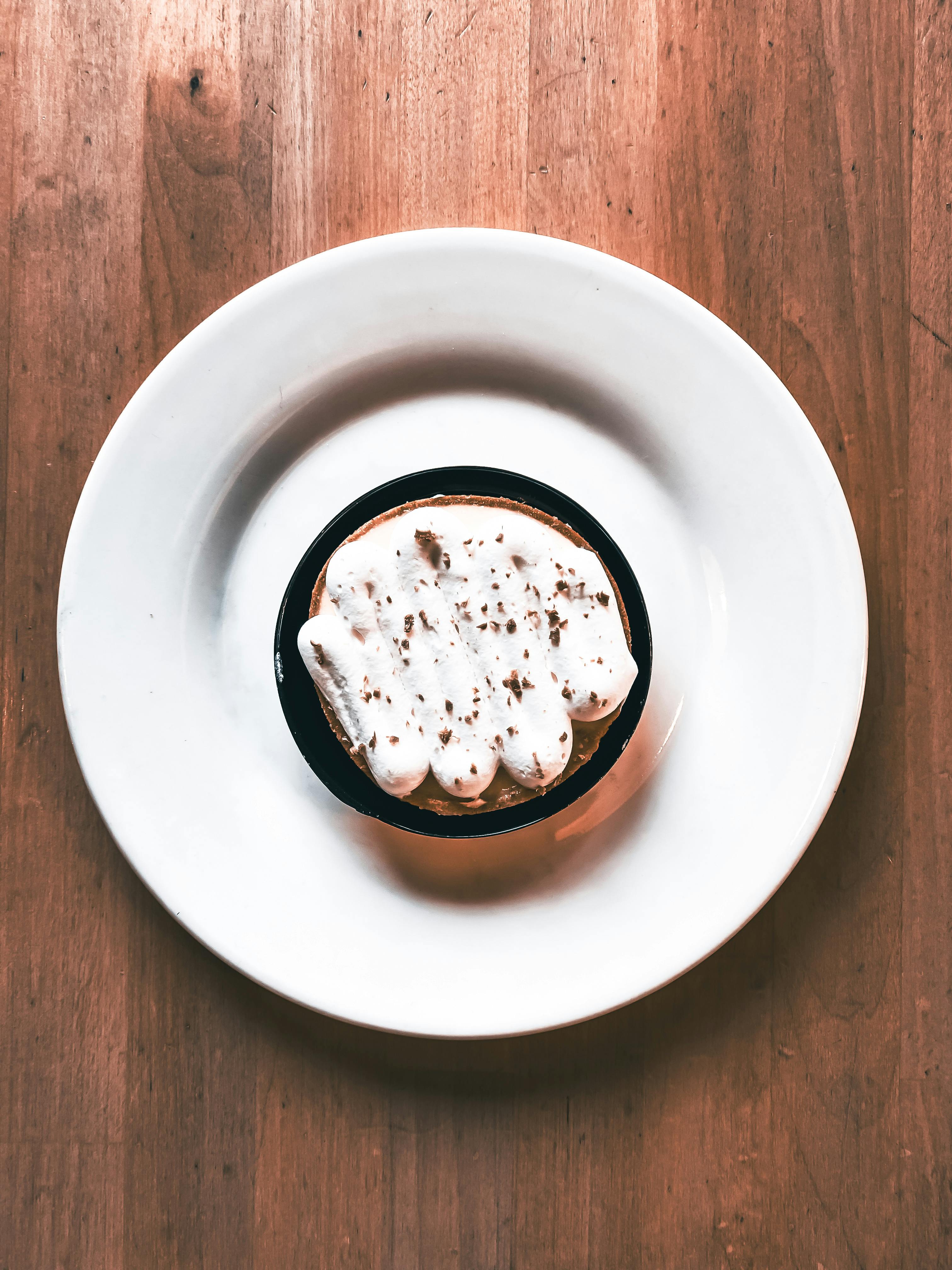 Gratis Veduta artistica dall'alto di un dessert con panna montata su un tavolo di legno, un esempio di minimalismo. Foto a disposizione