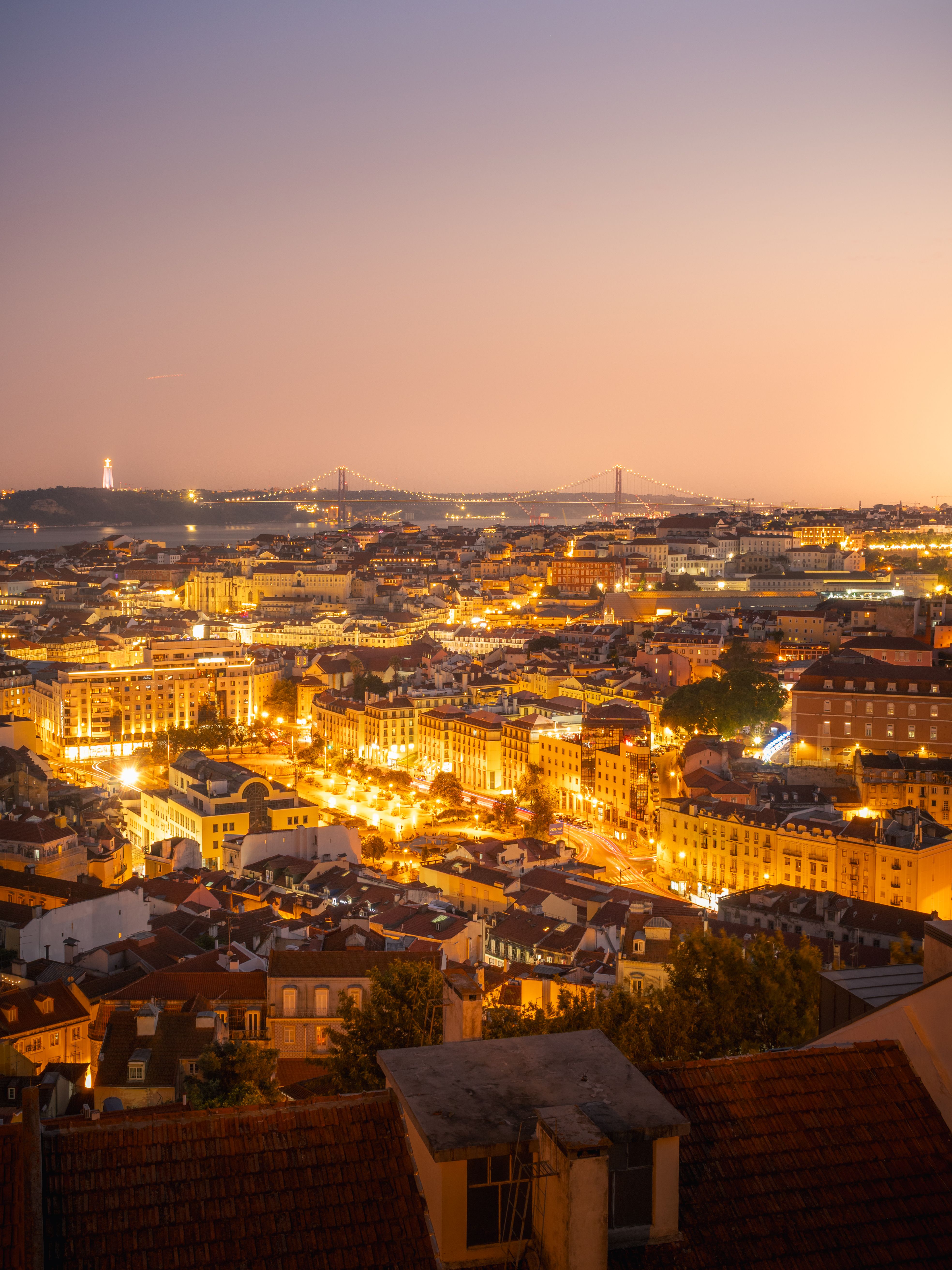 Stunning aerial view of Lisbon's illuminated cityscape during twilight, showcasing iconic architecture.