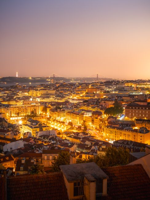 Stunning aerial view of Lisbon's illuminated cityscape during twilight, showcasing iconic architecture.