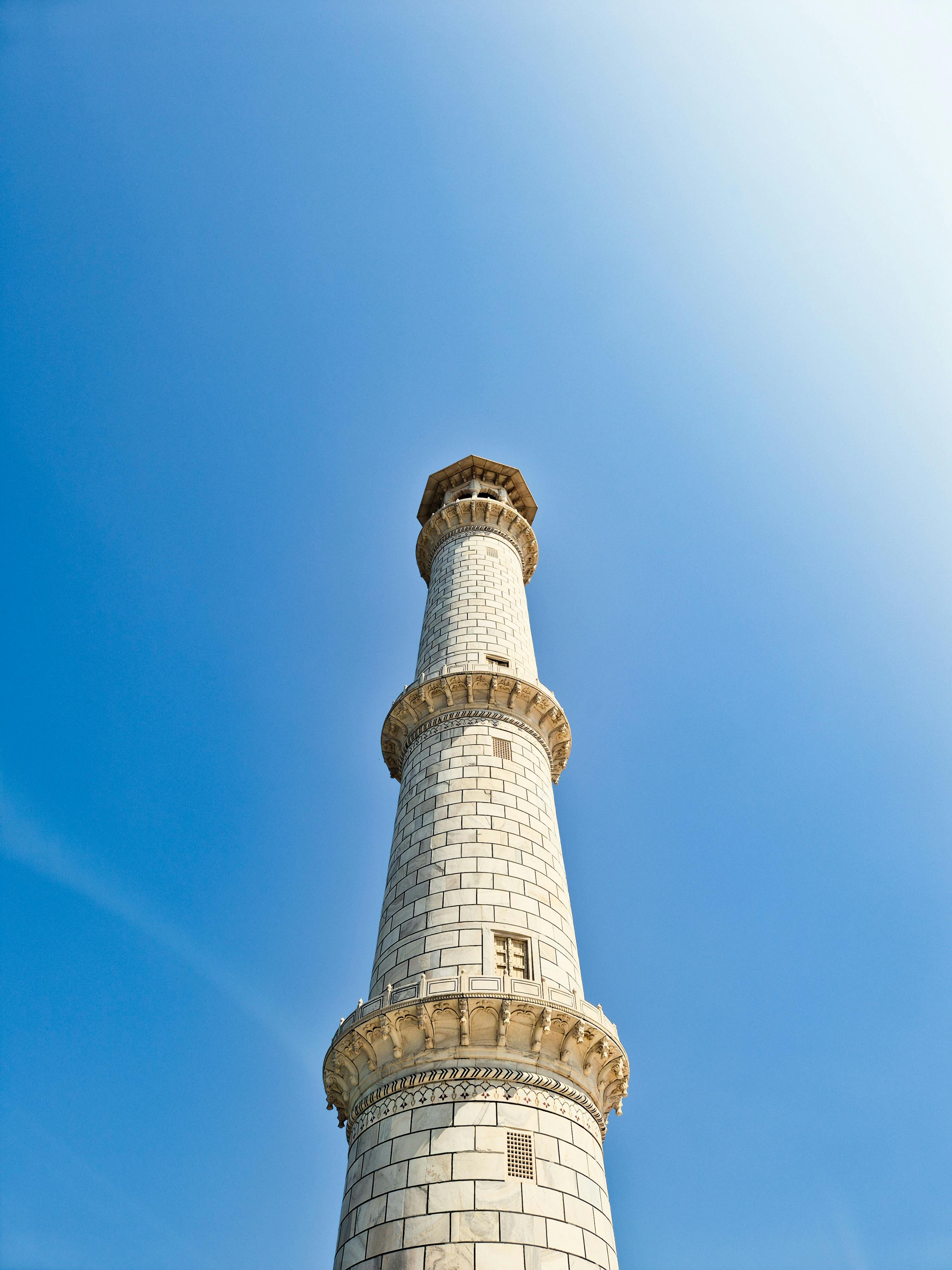 Kostenlos Ein hoher Marmorturm, der sich in den leuchtend blauen Himmel erhebt und klassische Architektur präsentiert. Stock-Foto