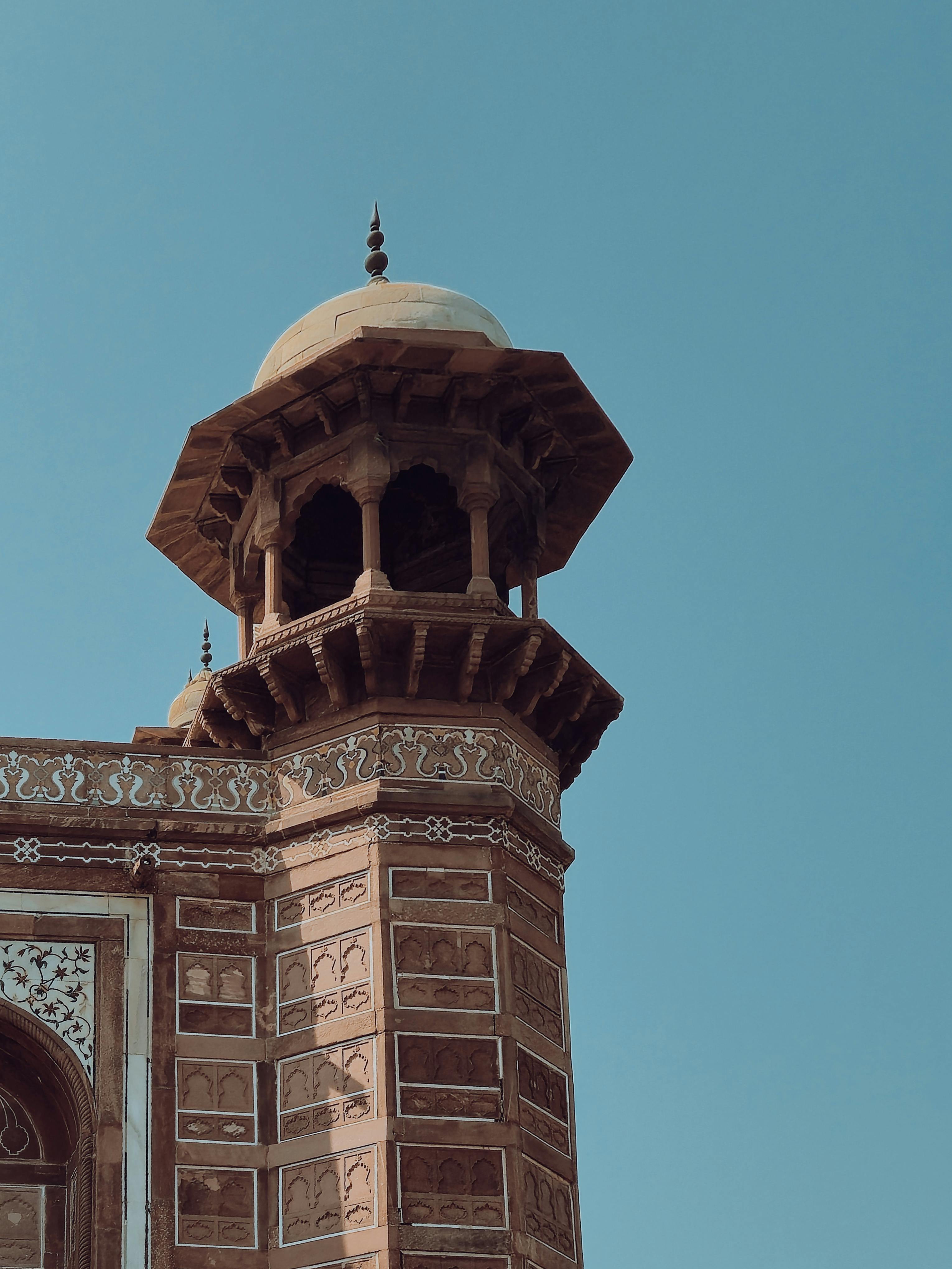 無料 澄み切った青空を背景に、精緻な装飾が施された歴史的な赤い砂岩の塔をクローズアップで撮影した写真。 写真素材