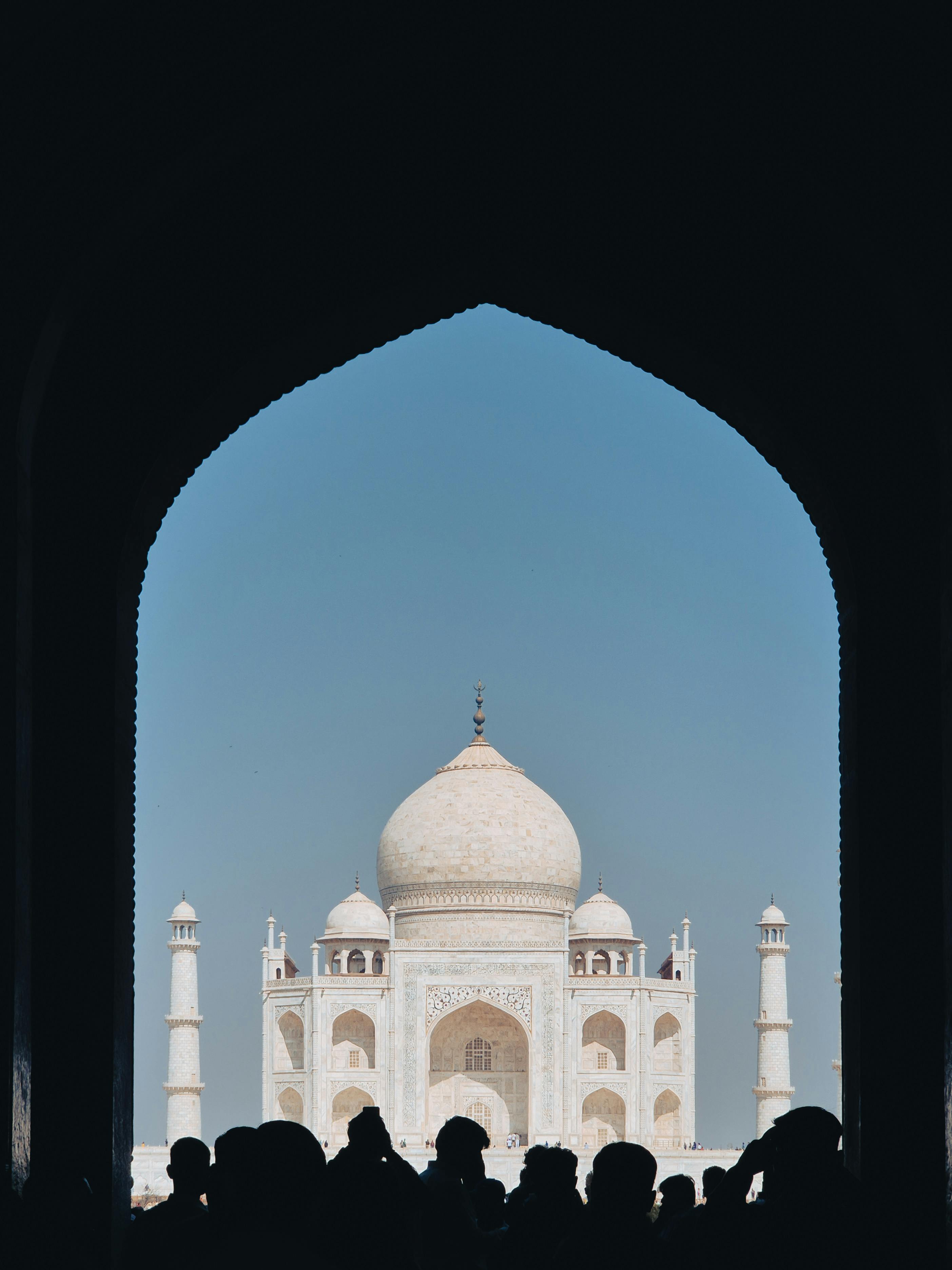 Ücretsiz Berrak bir gökyüzü altında, Tac Mahal'in muhteşem manzarasını çerçeveleyen insan silüetleri. Stok Fotoğraflar