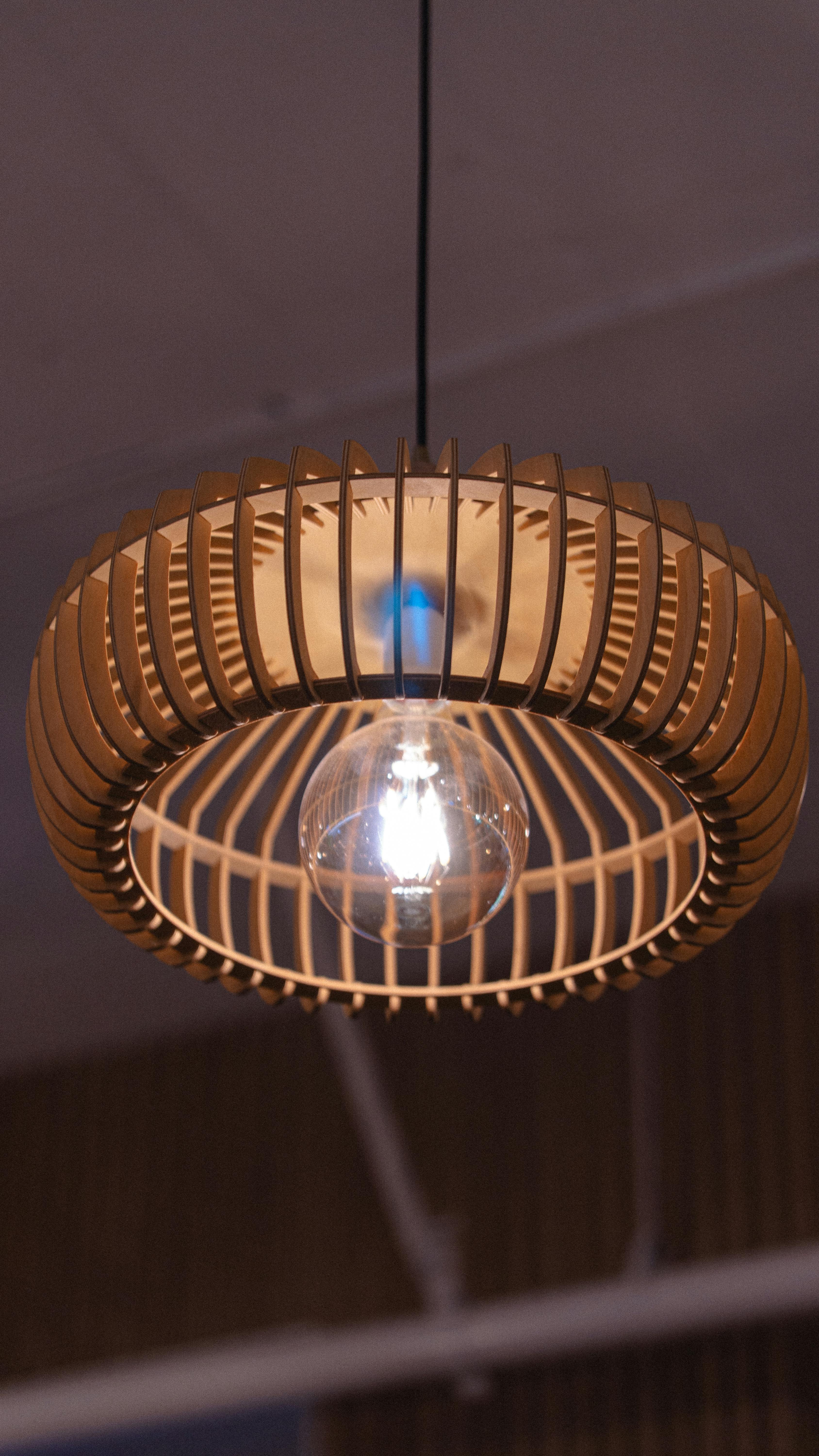 Gratis Elegante lampada a sospensione in legno con lampadina a vista, ideale per interni moderni. Foto a disposizione