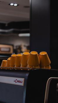 Stylish yellow cups arranged on an espresso machine in a modern café interior.
