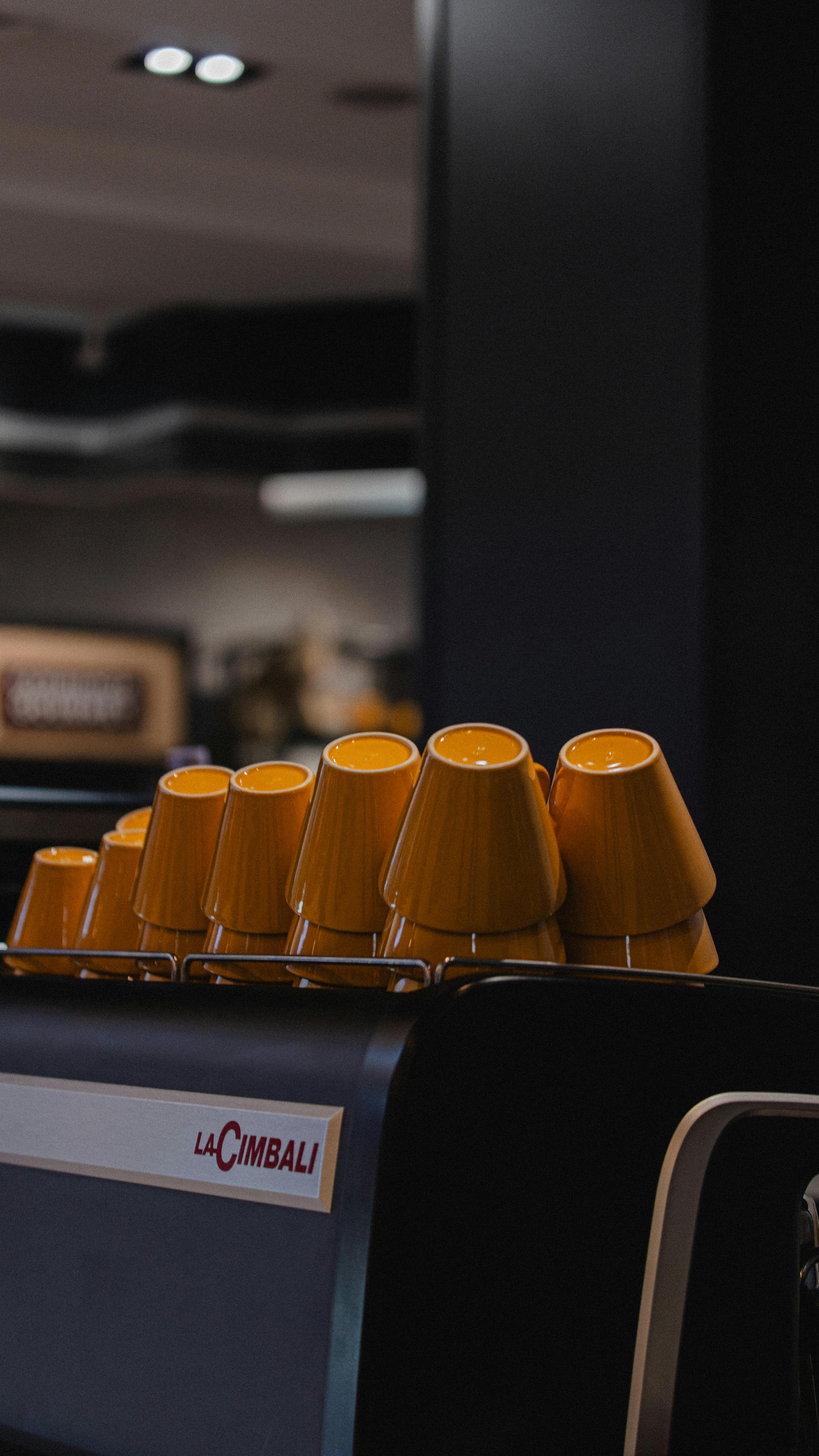 bezplatná Stylové žluté šálky uspořádané na espresso kávovaru v moderním interiéru kavárny. Základová fotografie