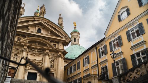 Free View of baroque architectural buildings with ornate details under a cloudy sky in a European city. Stock Photo