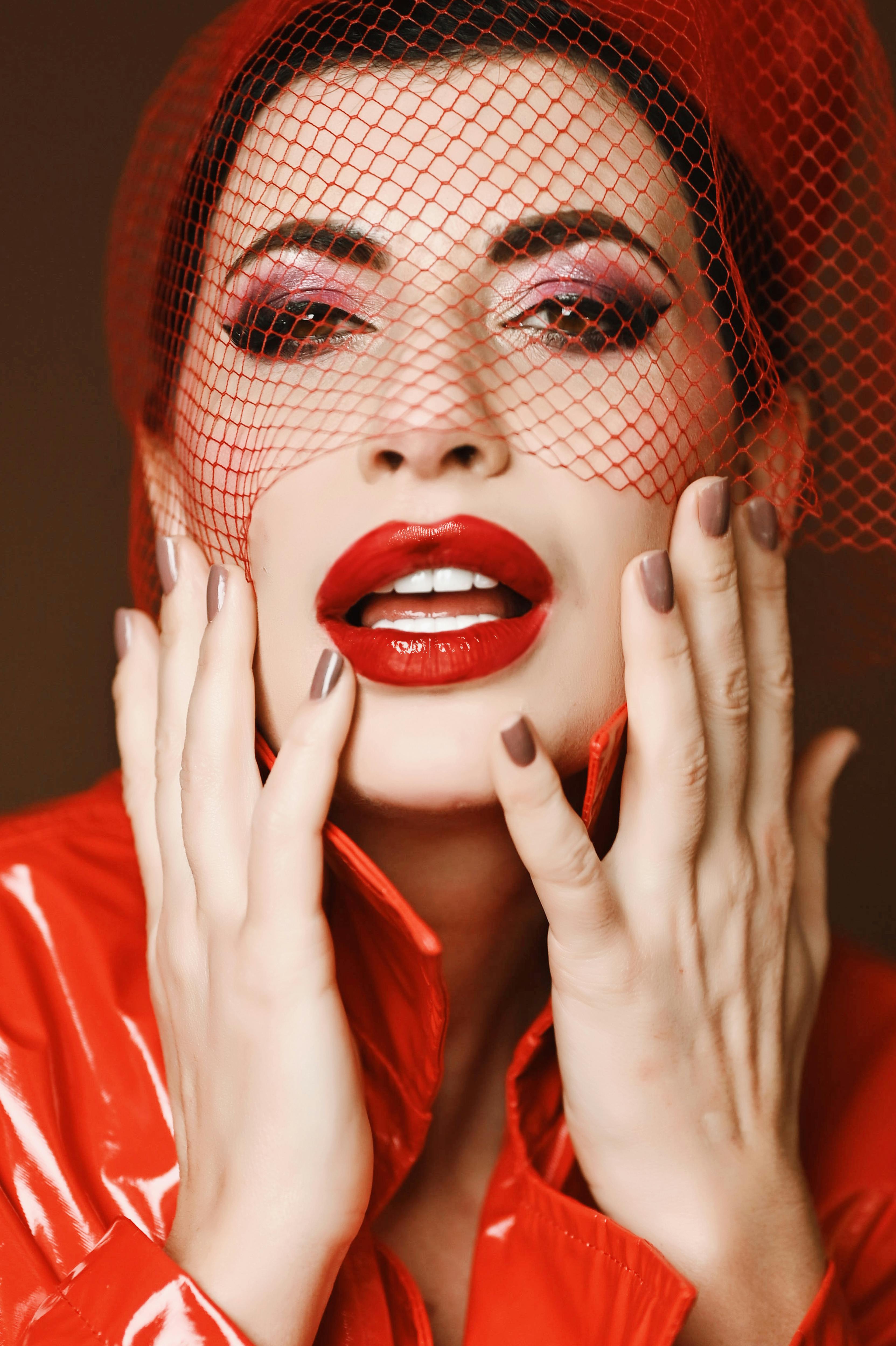 Miễn phí Ảnh chân dung cận cảnh một người phụ nữ với lớp trang điểm đỏ nổi bật và phụ kiện lưới. Ảnh lưu trữ
