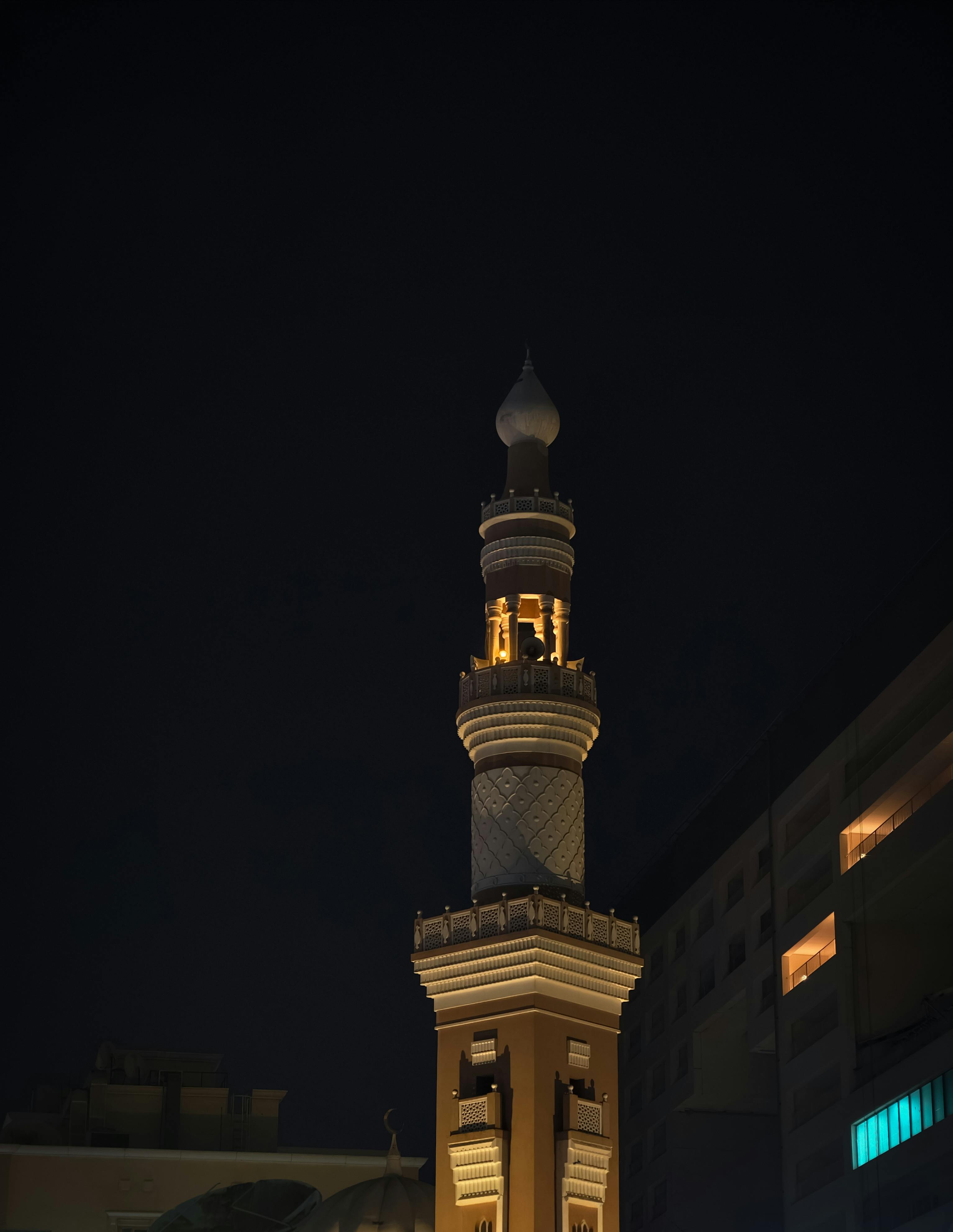 Kostenlos Ein wunderschön beleuchtetes Minarett vor einem ruhigen Nachthimmel, das die islamische Architektur eindrucksvoll präsentiert. Stock-Foto