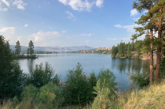 Beautiful lake surrounded by pine trees and mountains under a clear blue sky.