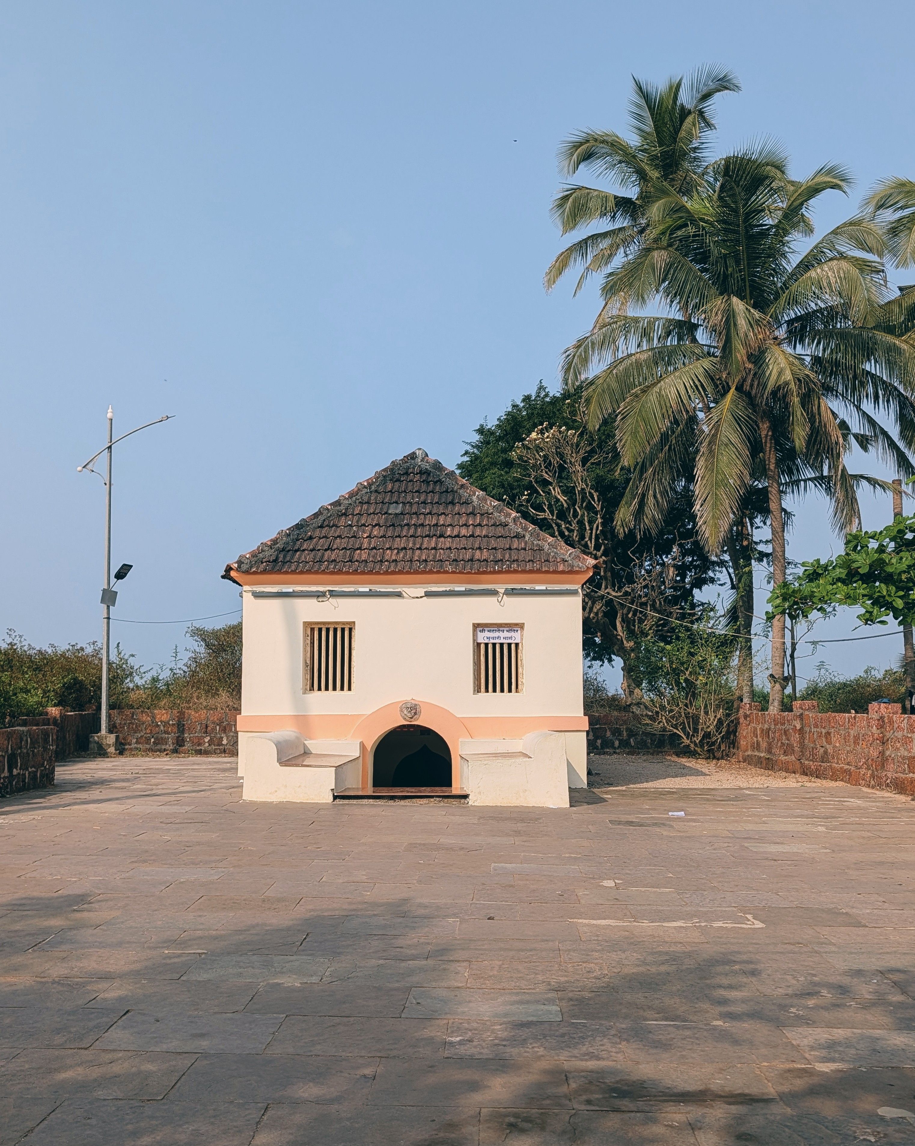 Charming historic building surrounded by lush palm trees under a clear blue sky in India.