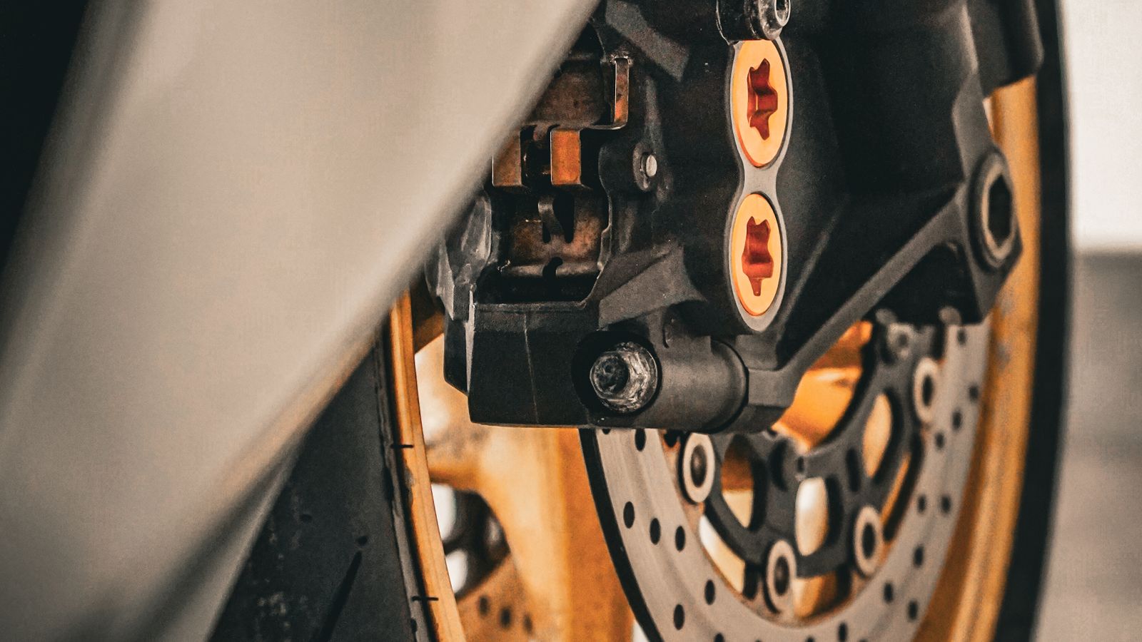 Detalhe do pneu dianteiro de uma moto usada sendo inspecionado quanto ao desgaste irregular