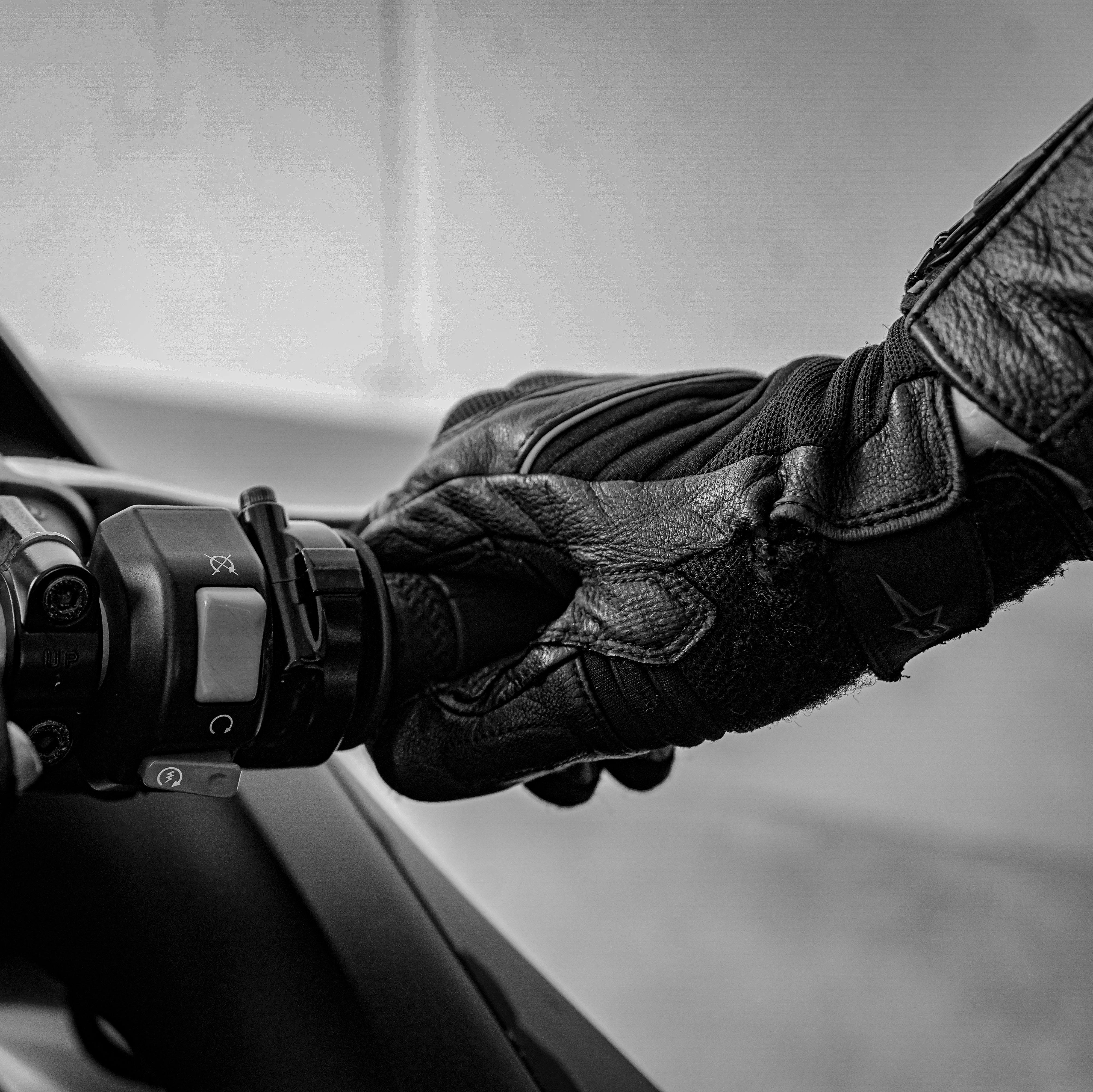 gratis Een gedetailleerde zwart-witfoto van een gehandschoende hand die een motorstuur vastgrijpt. Stockfoto