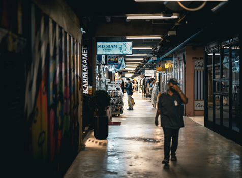 Capture of a bustling indoor market in Bangkok, Thailand with vibrant signage and locals walking.