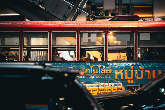 Street view of people inside a Bangkok bus, showcasing urban life and transportation.