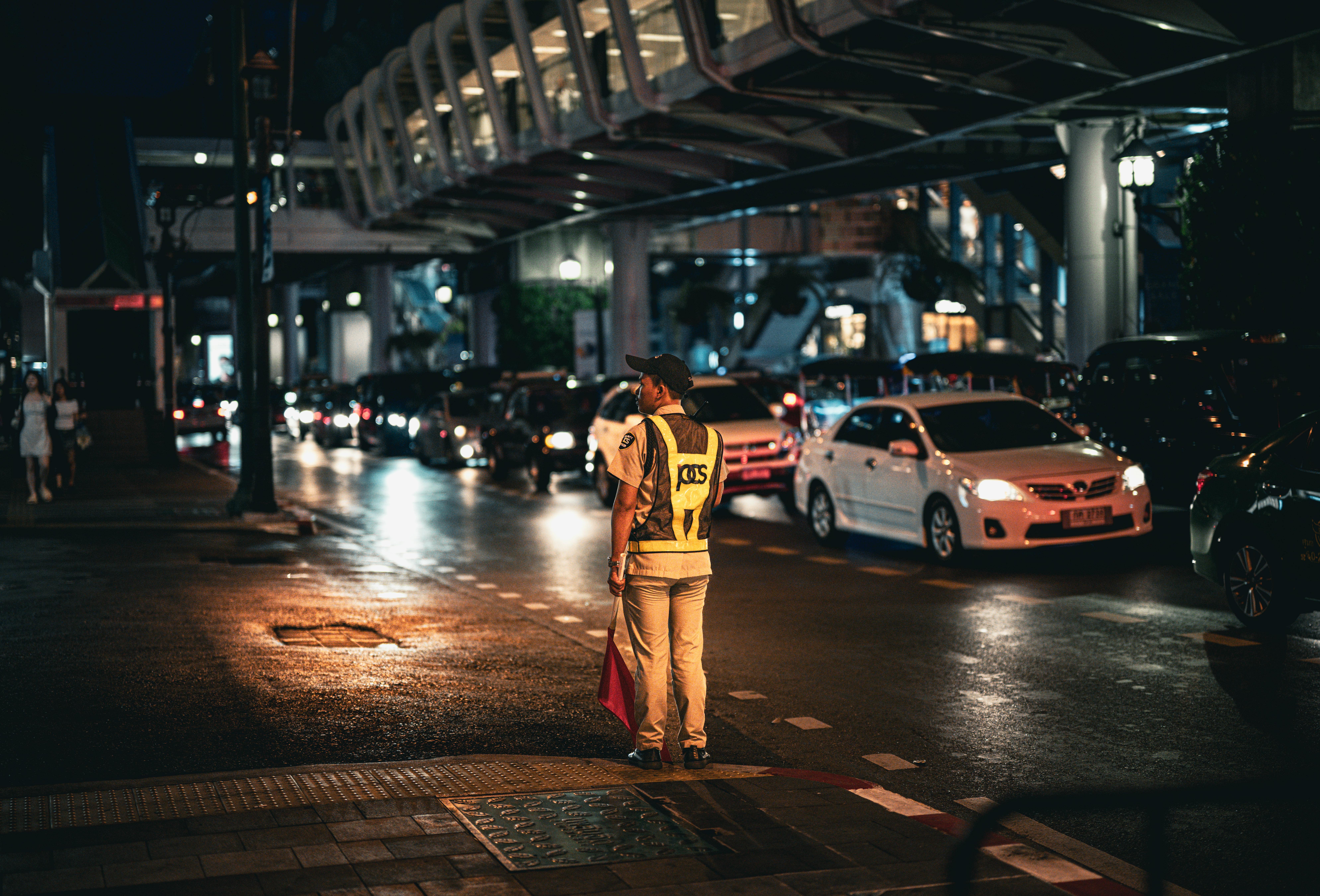 Gratis Un agente della polizia stradale dirige il traffico intenso di notte a Bangkok, in Thailandia. Foto a disposizione