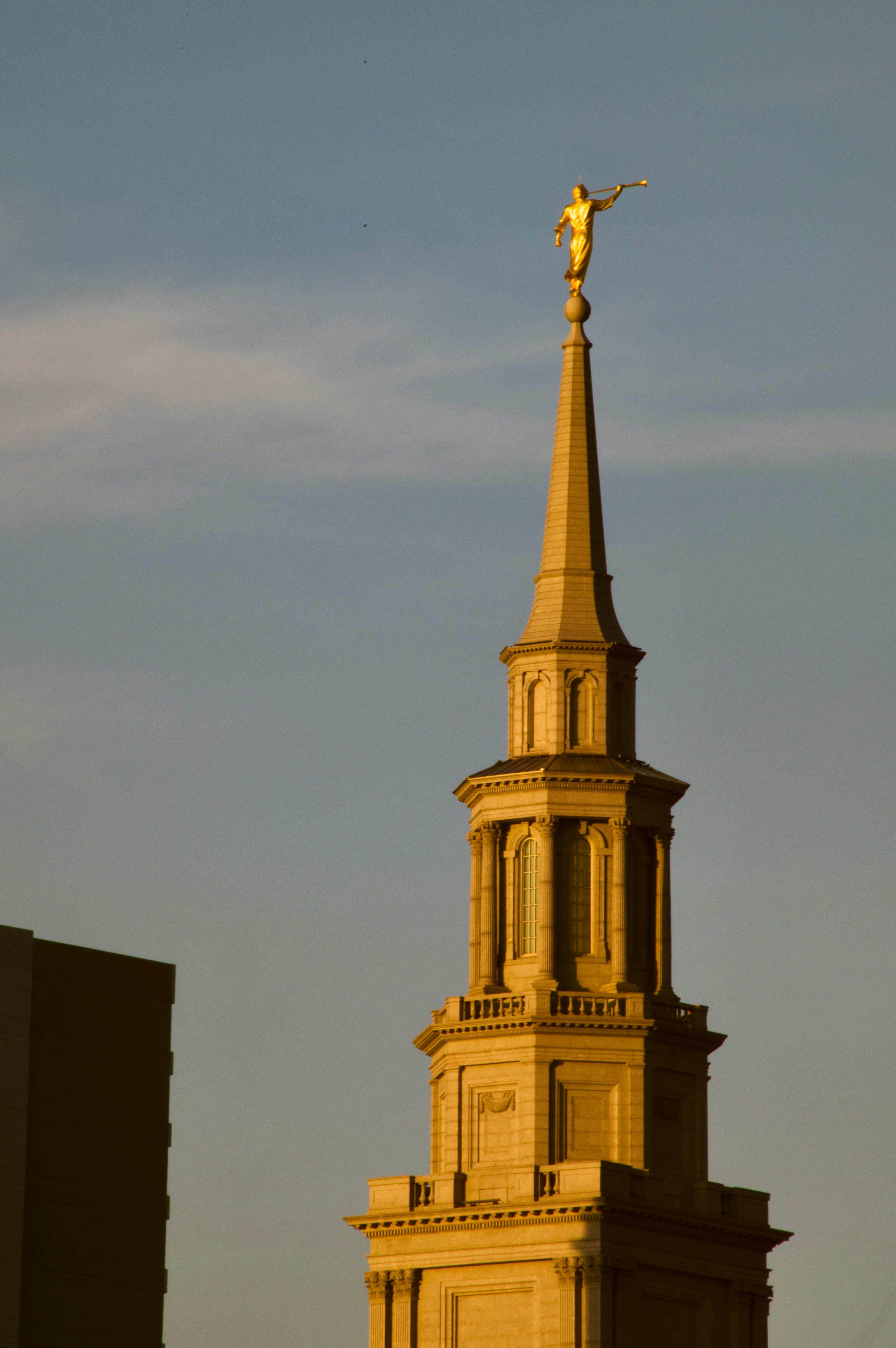 無料 夕暮れ時の澄み切った青空を背景に、神殿の尖塔の上に立つ黄金の天使モロナイ像。 写真素材