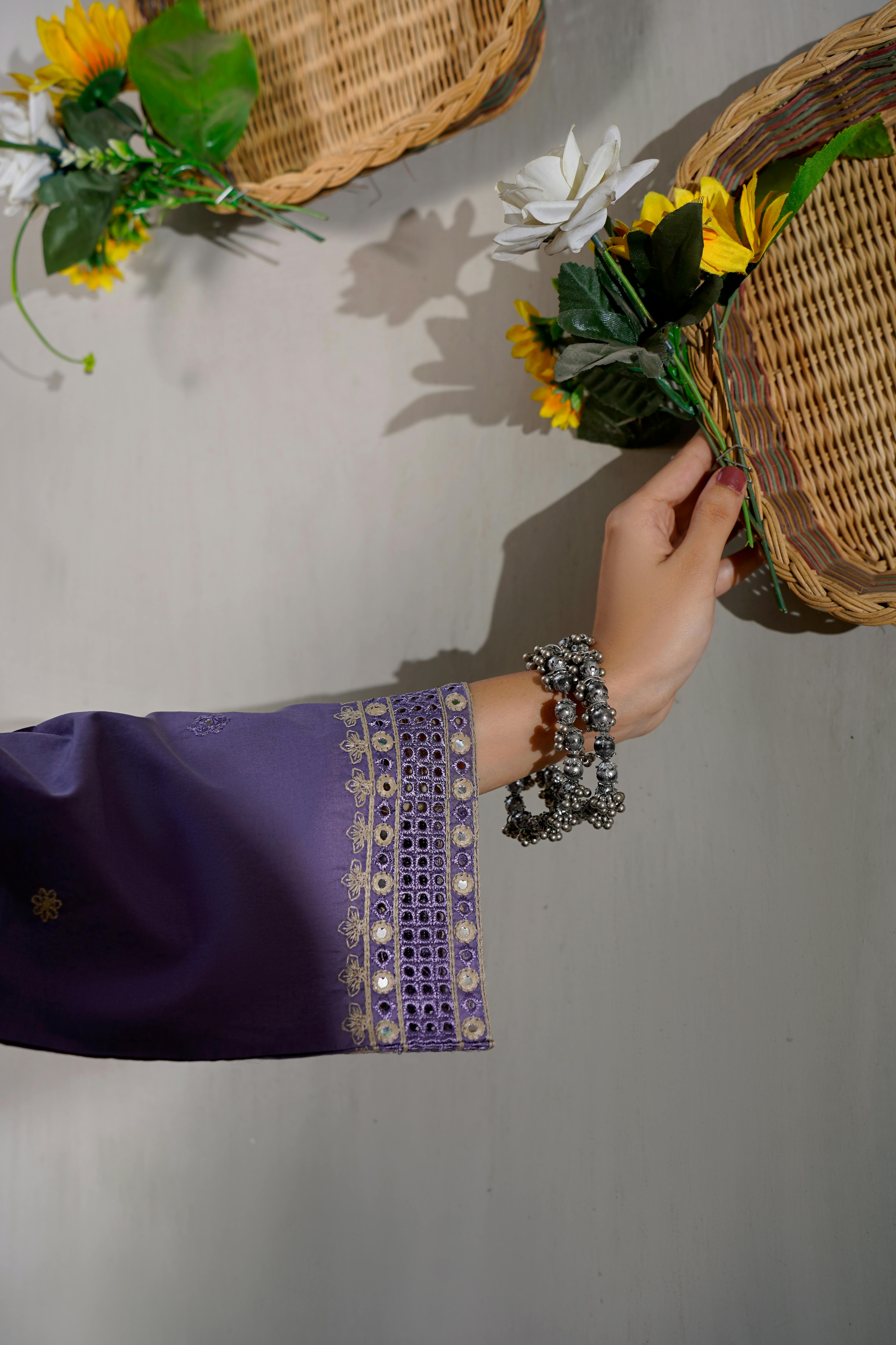 Gratuit O mânecă brodată violet se întinde spre coșuri de răchită și floarea-soarelui într-o compoziție elegantă. Fotografie de stoc