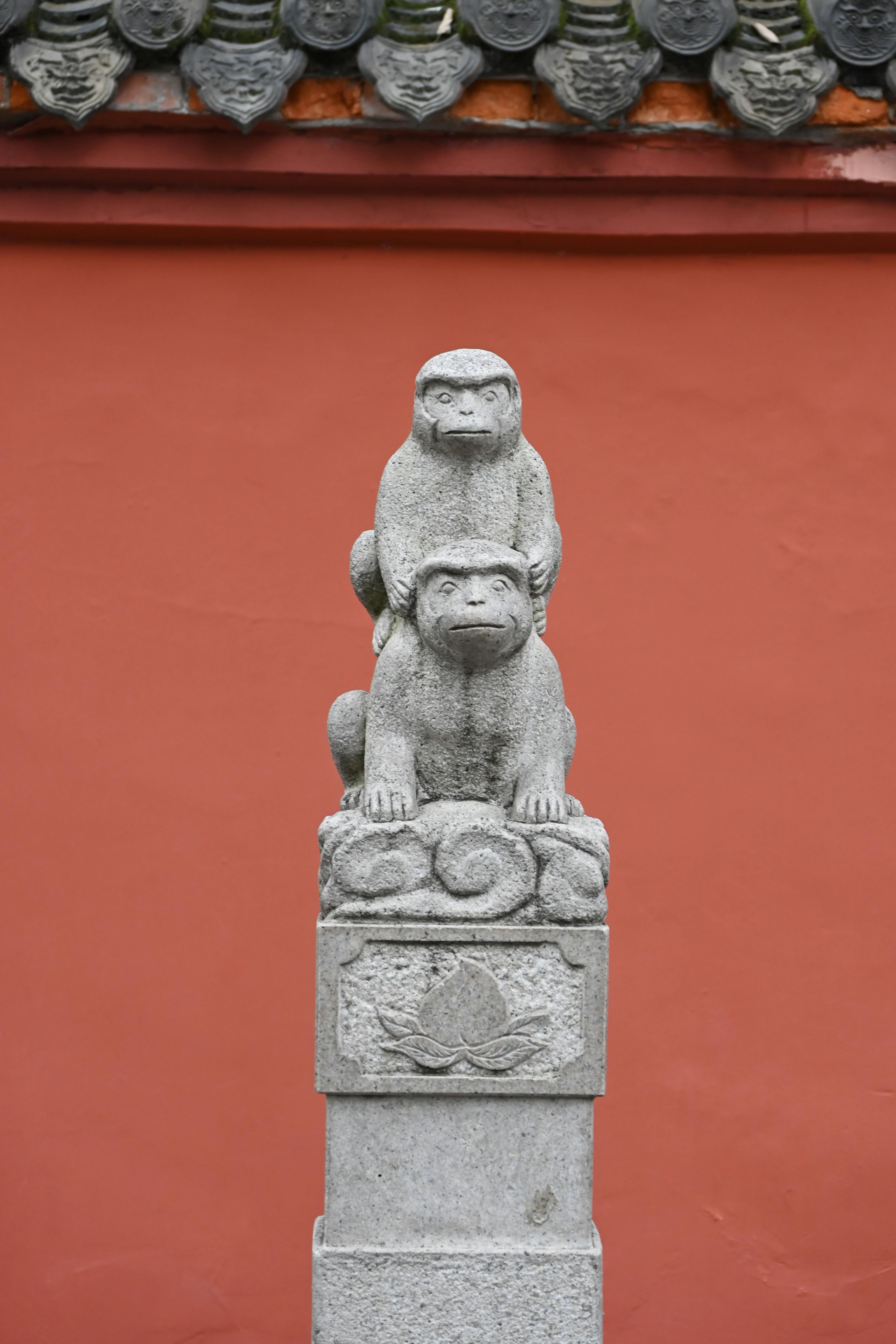 Gratis Dos estatuas de monos de piedra sobre un pedestal, frente a una pared roja tradicional. Foto de stock