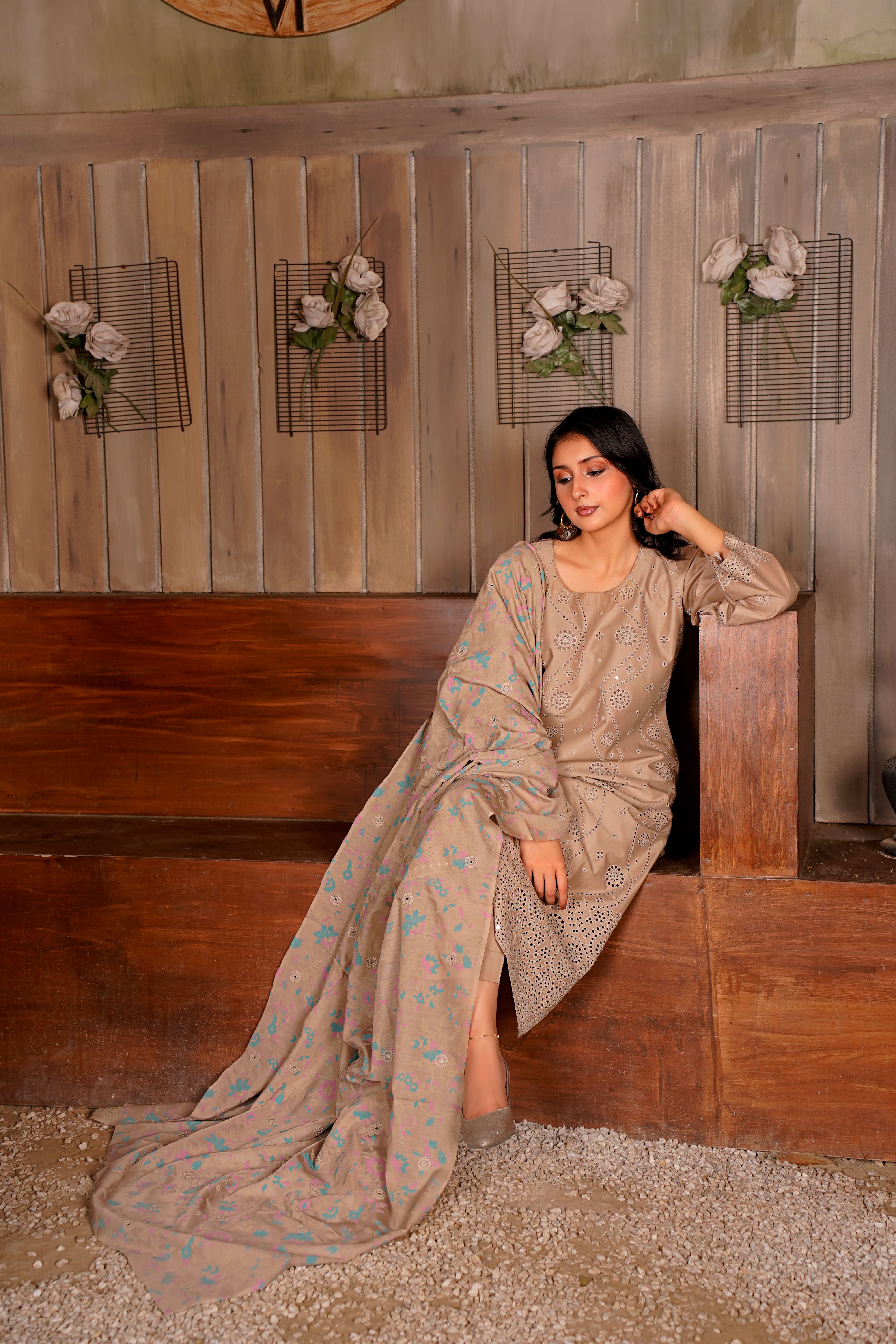 Fashionable woman in embroidered Eastern attire seated elegantly indoors.