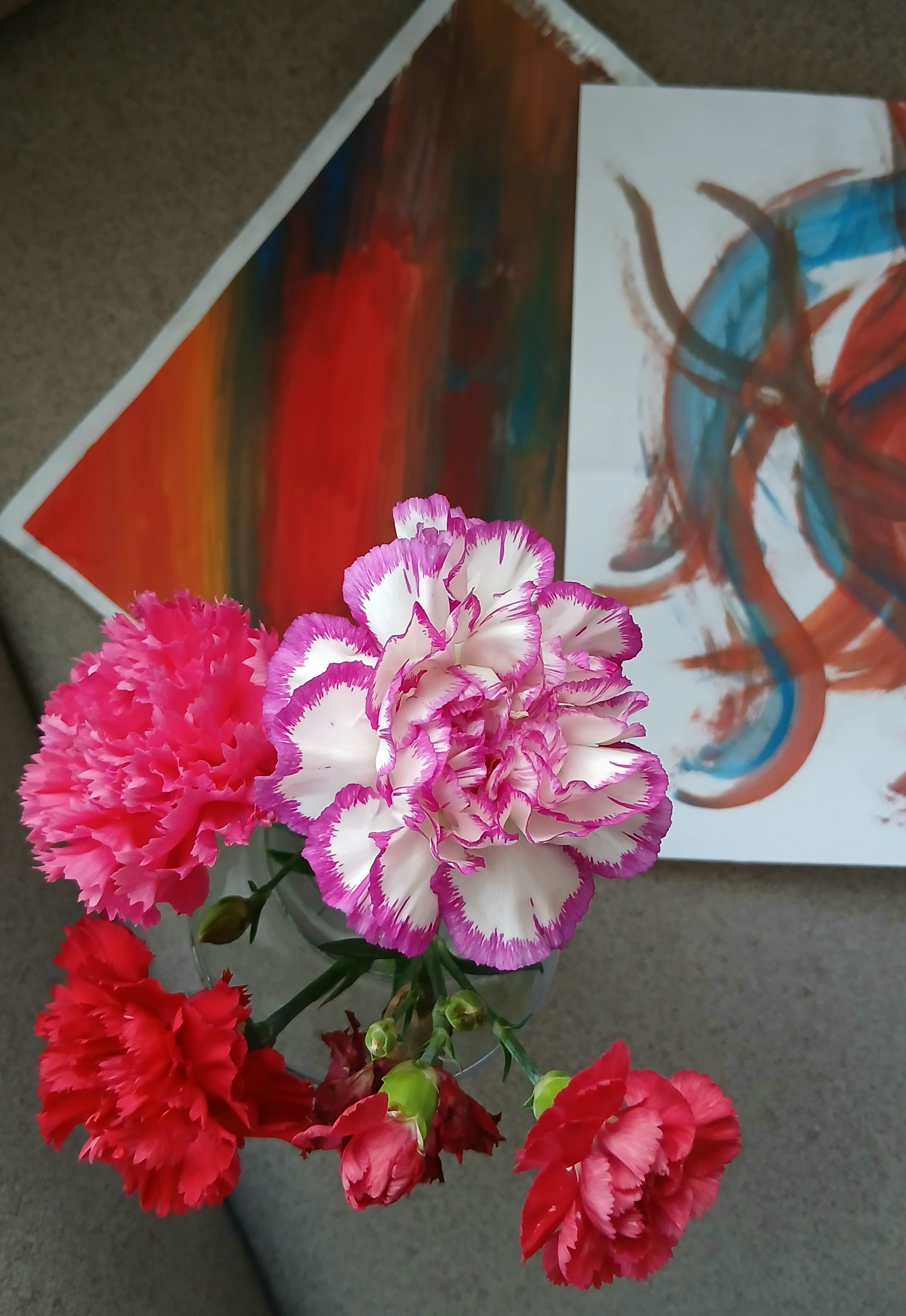 [ColoSach]-artistic-arrangement-of-vivid-carnations-against-abstract-paintings,-showcasing-colorful-elements.