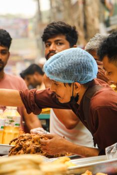 A bustling street food scene in Dhaka with a vendor serving customers. Captured with dynamic action and vibrant atmosphere.