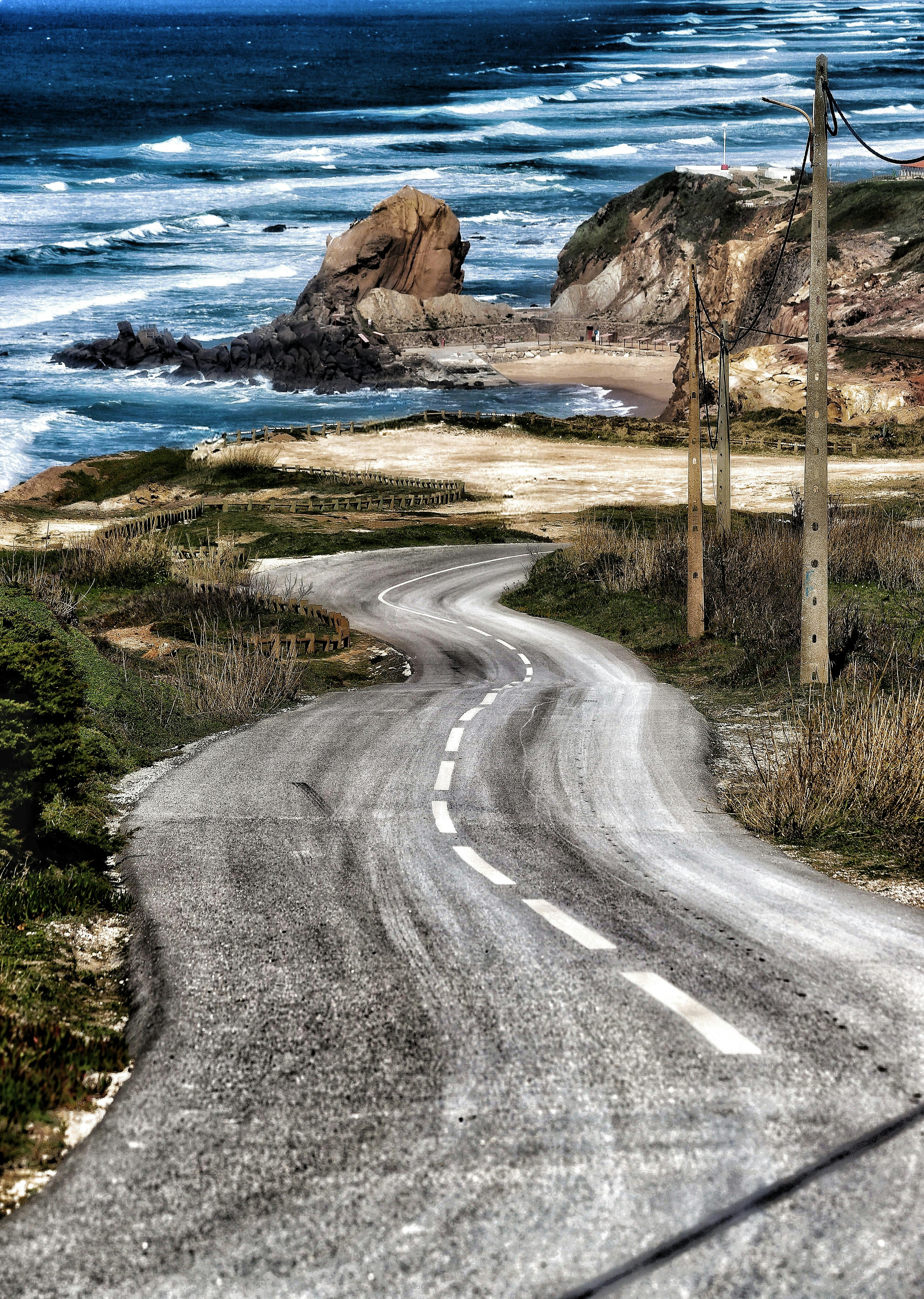Gratis Vista spettacolare di una strada tortuosa lungo una costa frastagliata, battuta dalle onde impetuose. Foto a disposizione