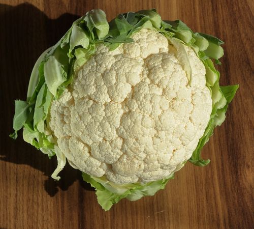 Free Top view of a whole raw cauliflower on a wooden background, perfect for healthy food concepts. Stock Photo