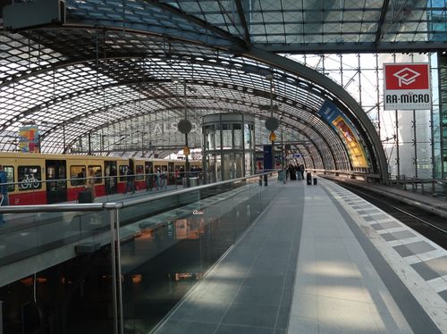 Free Commuters at a bustling train station with modern glass and steel architecture. Stock Photo