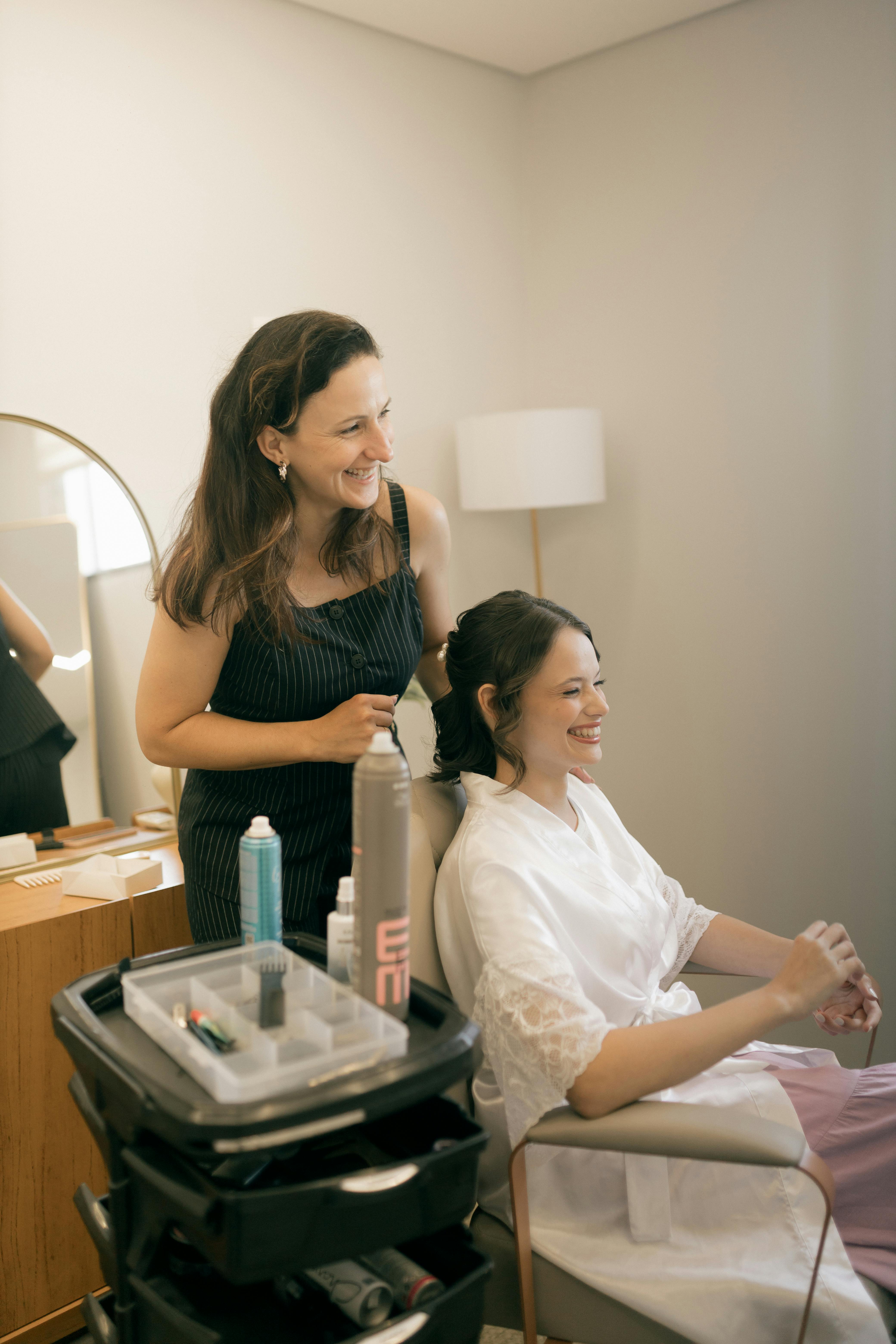 無料 花嫁がヘアスタイリストと一緒に、落ち着いた室内で結婚式の準備をしている様子を、自然な瞬間を捉えた写真。 写真素材