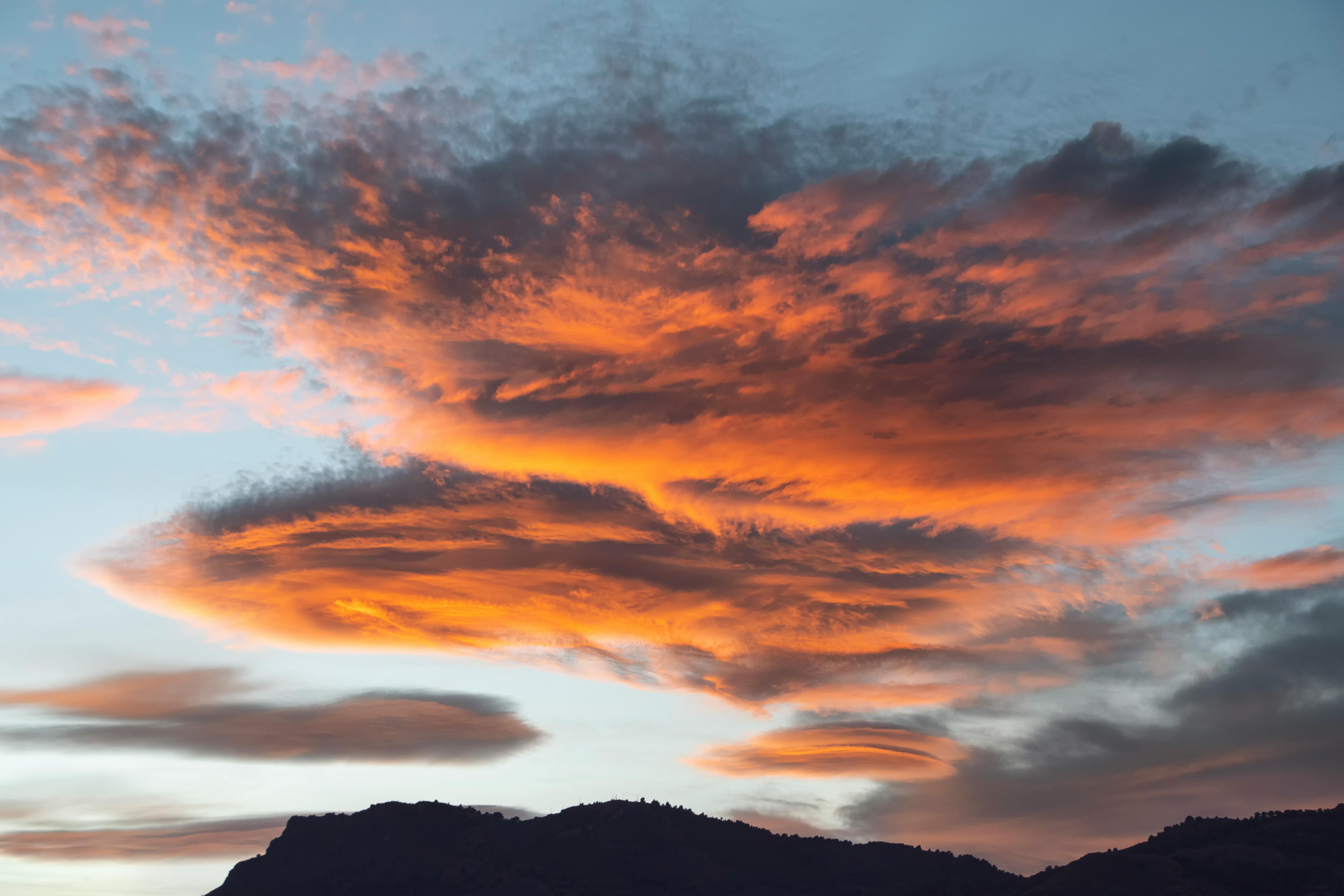 Gratis Un tramonto mozzafiato con nuvole infuocate che si stagliano contro le montagne, perfetto per temi naturalistici e di viaggio. Foto a disposizione