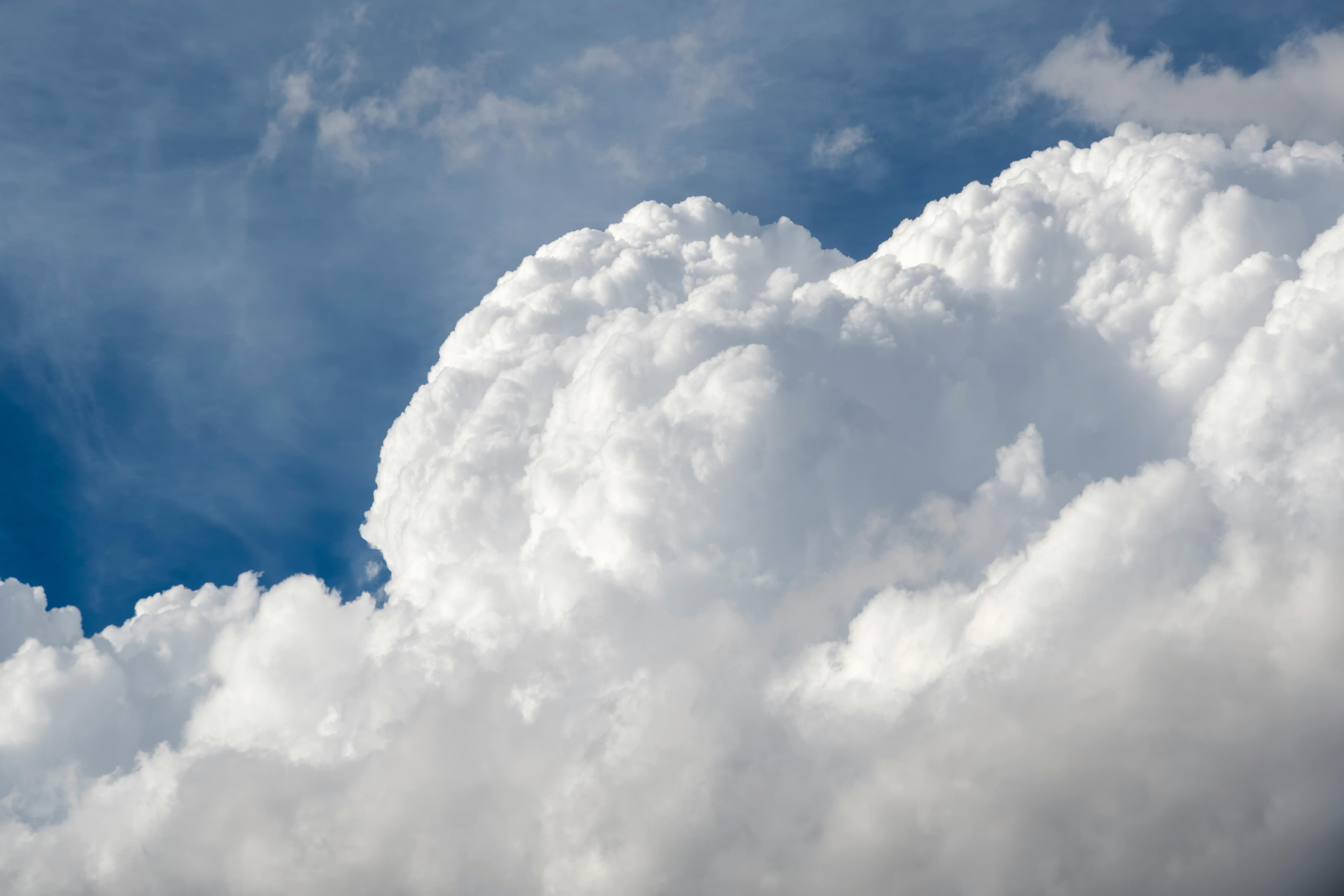 Gratuit Des cumulus lumineux se dressent sur un ciel d'un bleu éclatant, témoignant de la beauté sereine de l'été. Photos
