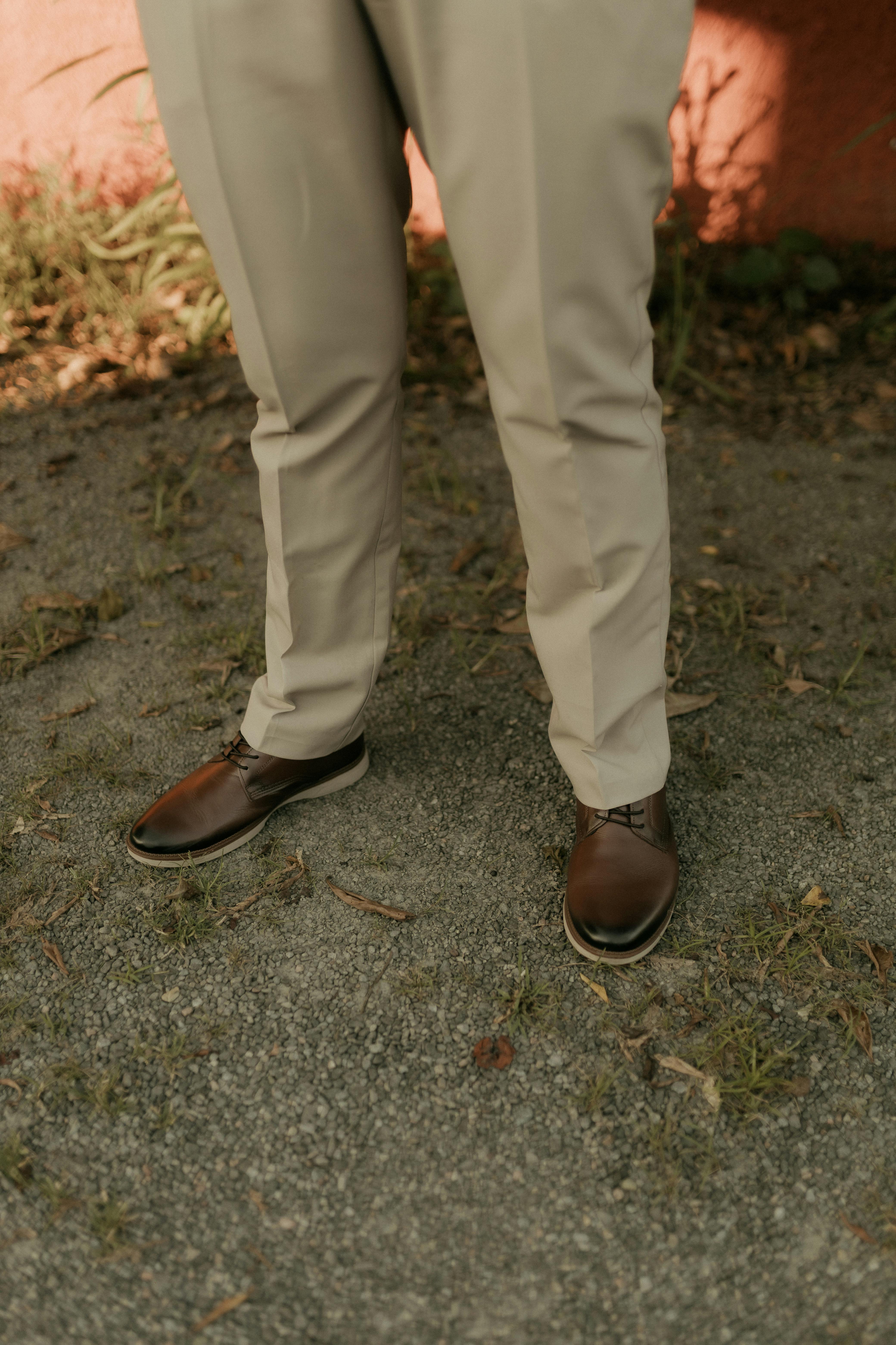 gratis Close-up van stijlvolle bruine geklede schoenen gecombineerd met een lichtbeige broek, buiten op een zonnige dag. Stockfoto