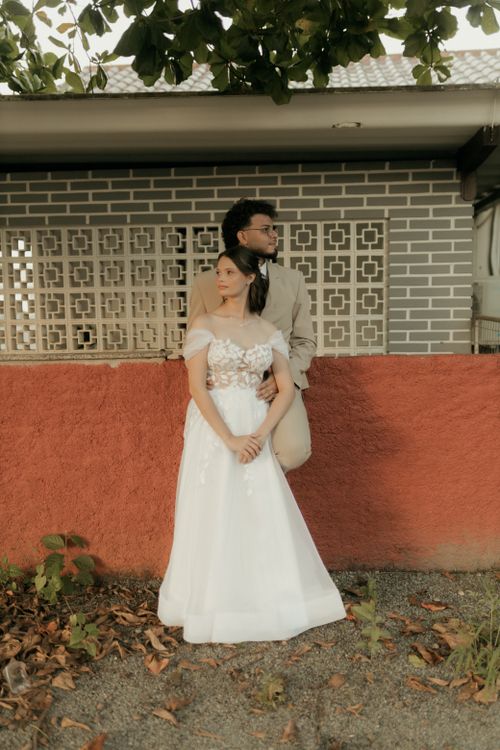 Free Charming portrait of a couple in formal attire against a rustic background, ideal for wedding themes. Stock Photo