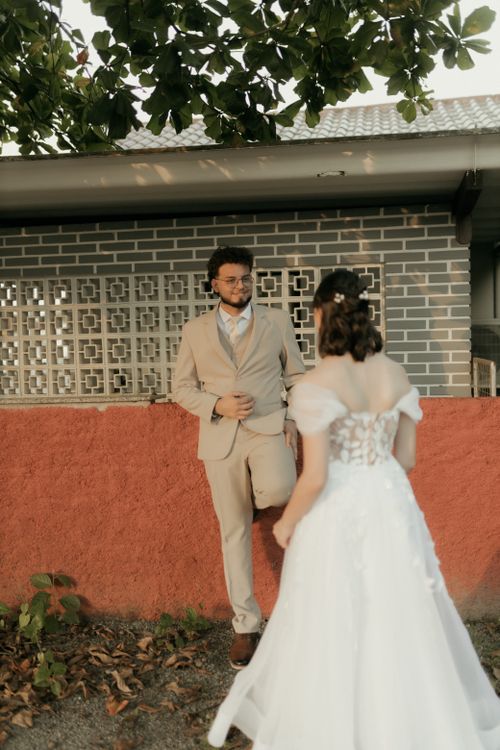 Free A bride and groom in an outdoor setting, capturing a romantic moment before a brick wall. Stock Photo