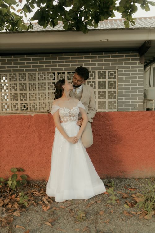 Free A joyful married couple embraces against a colorful wall outdoors, surrounded by natural scenery. Stock Photo