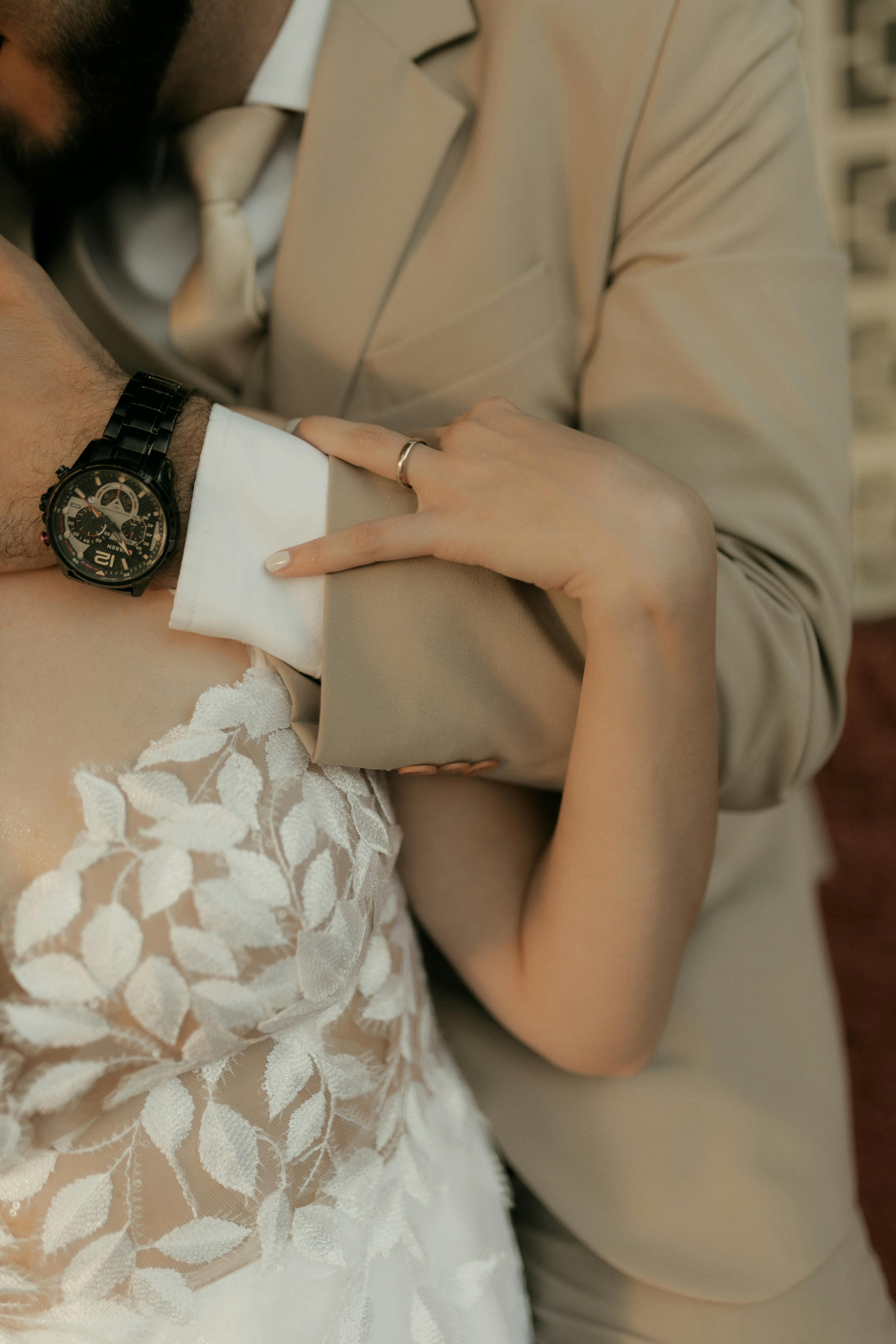 De franc Moment íntim entre la núvia i el nuvi amb vestits elegants, destacant els detalls del rellotge i el vestit floral. Foto d'estoc